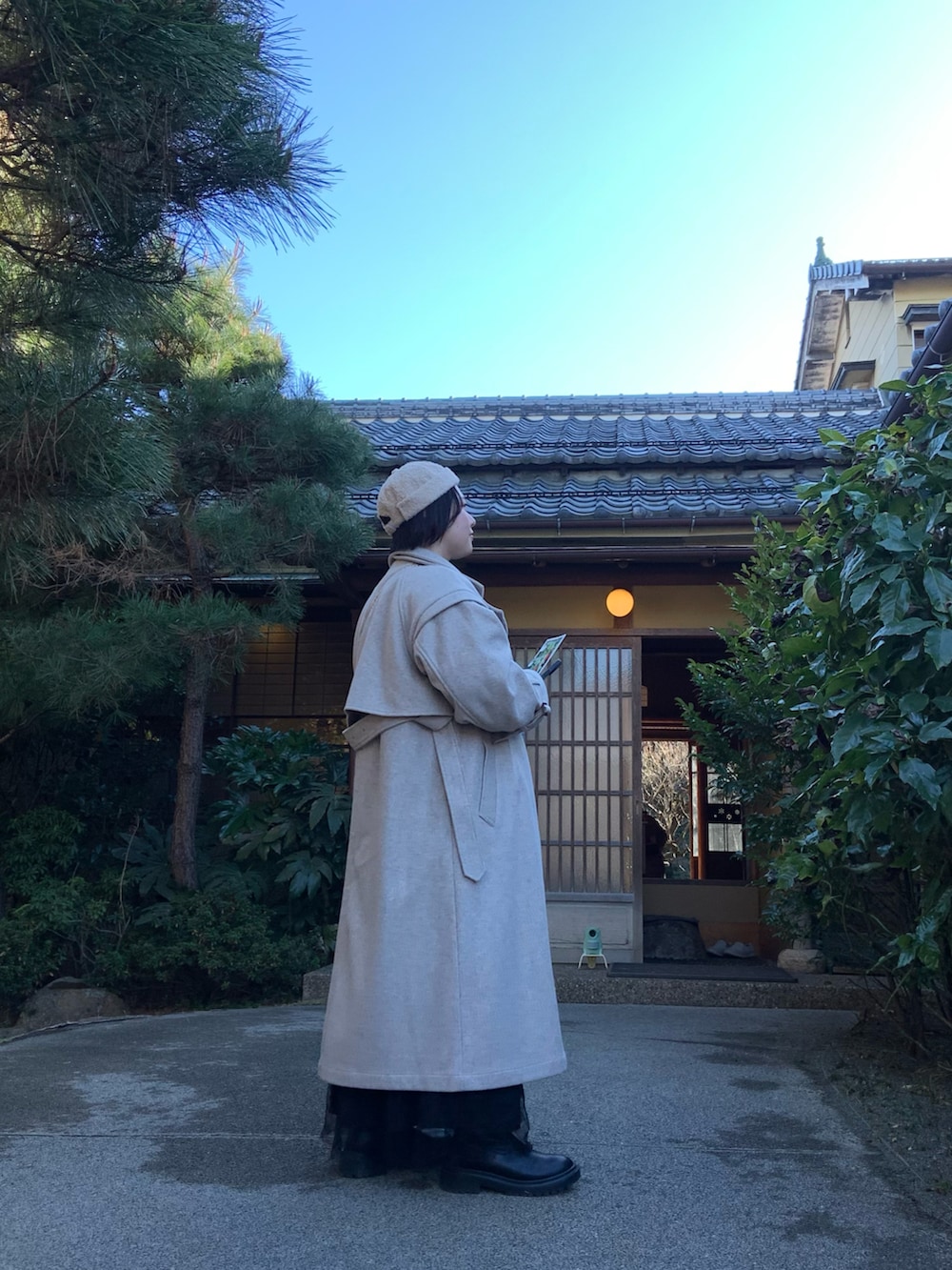 ベージュ系のチェスターコート、ブラック系のスカート、ベージュ系の帽子を着用したレディースの春コーディネートの2枚目の写真