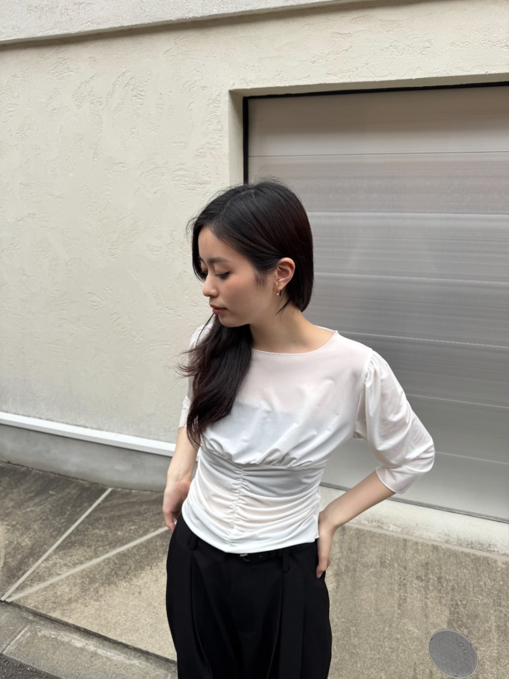 ブラック系のスラックス、ホワイト系のTシャツ/カットソー、シルバー系のイヤーカフを着用したレディースの春コーディネートの2枚目の写真