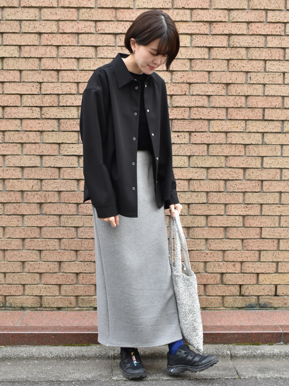 ブラック系のワンピース、グレー系のスカート、シルバー系のトートバッグを着用したレディースの冬コーディネートの2枚目の写真