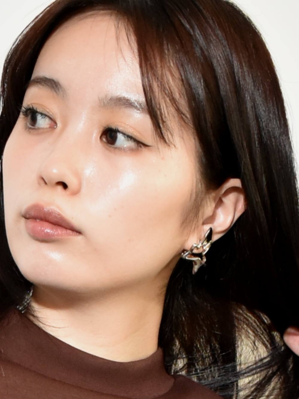 ブラウン系のスカート、ブラウン系のスウェット、シルバー系のイヤリングを着用したレディースの冬コーディネートの2枚目の写真