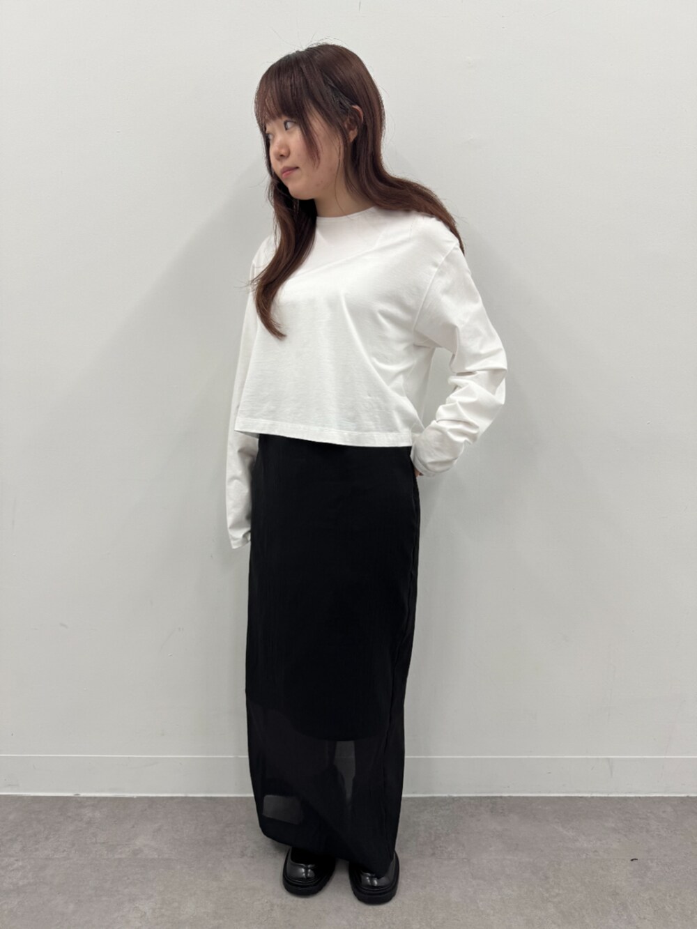 ブラック系のスカート、ホワイト系のTシャツ/カットソーを着用したレディースの春コーディネートの2枚目の写真