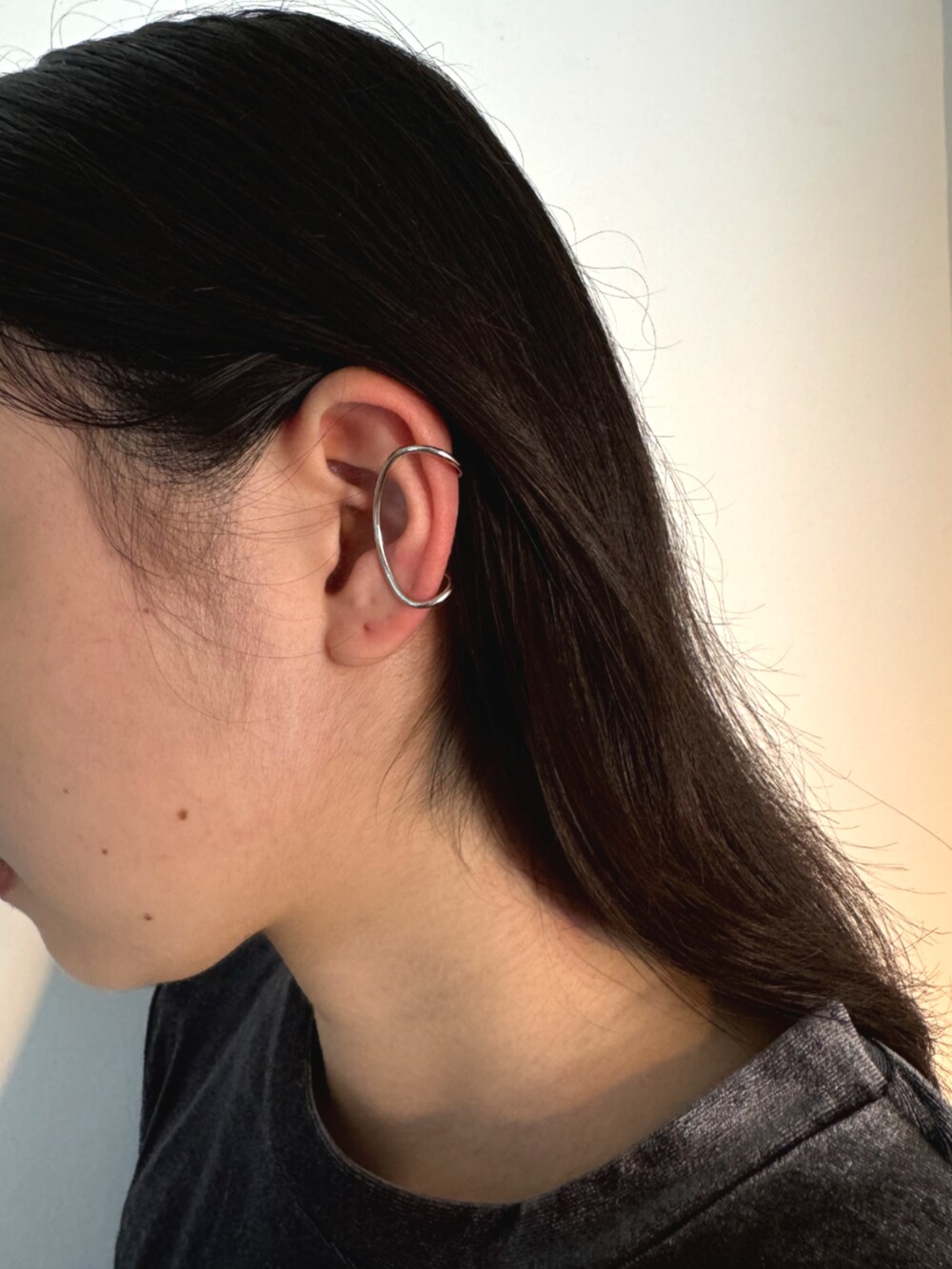 ブラック系のスカート、グレー系のTシャツ/カットソー、シルバー系のイヤーカフを着用したレディースの秋コーディネートの3枚目の写真