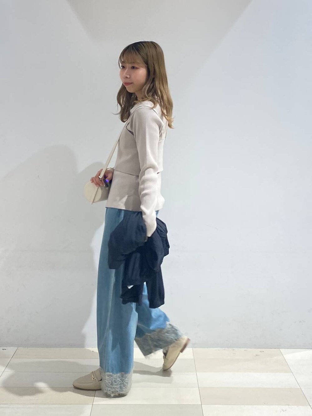 ベージュ系のTシャツ/カットソー、ホワイト系のクラッチバッグ、ホワイト系のローファーを着用したレディースの秋コーディネートの7枚目の写真