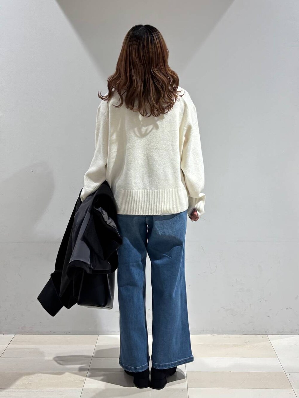 ブラック系のショルダーバッグ、ブラック系のチェスターコート、ホワイト系のニット/セーターを着用したレディースの冬コーディネートの3枚目の写真