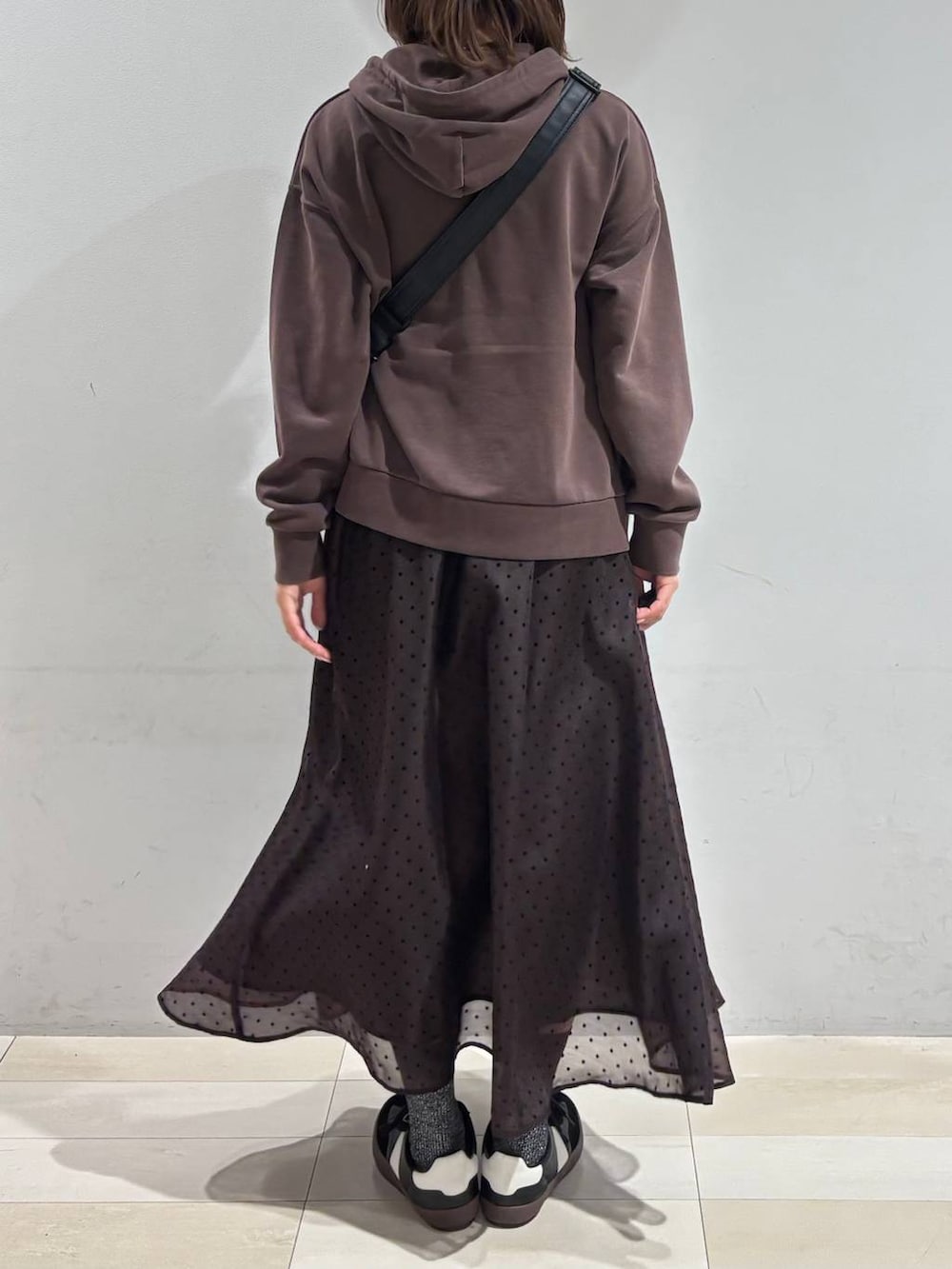 ブラック系のスニーカー、ブラック系のショルダーバッグ、ブラウン系のスカートを着用したレディースの春コーディネートの4枚目の写真