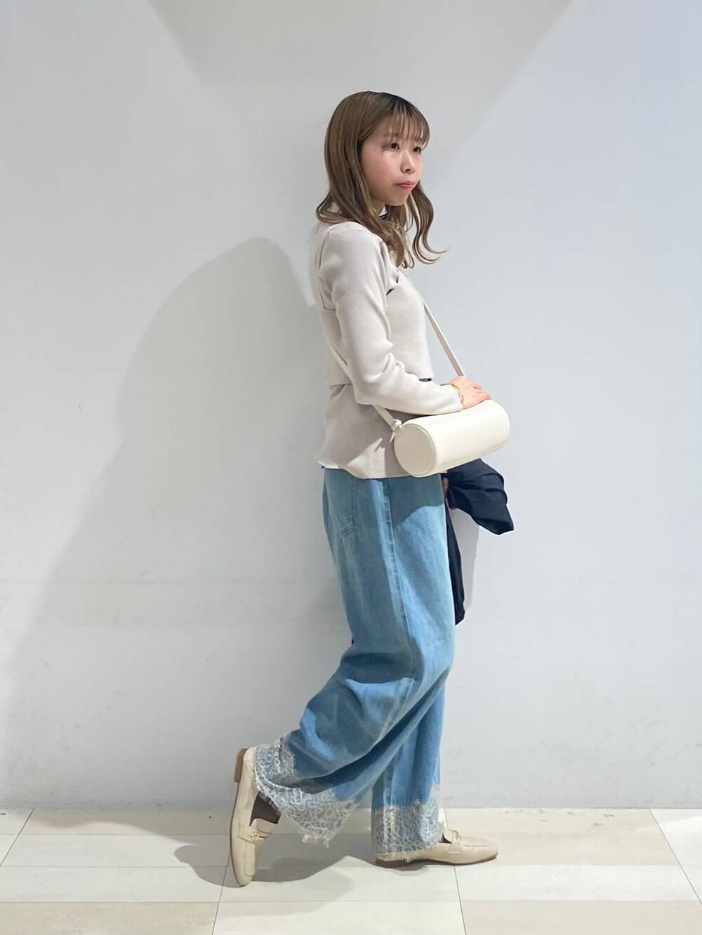 ベージュ系のTシャツ/カットソー、ホワイト系のクラッチバッグ、ホワイト系のローファーを着用したレディースの秋コーディネートの4枚目の写真