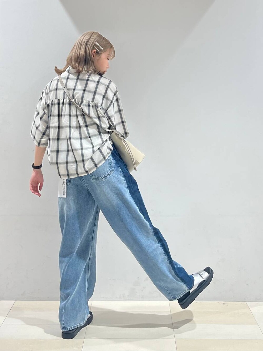 シルバー系のサンダル、ベージュ系のショルダーバッグ、ブルー系のデニムパンツを着用したレディースの夏コーディネートの4枚目の写真