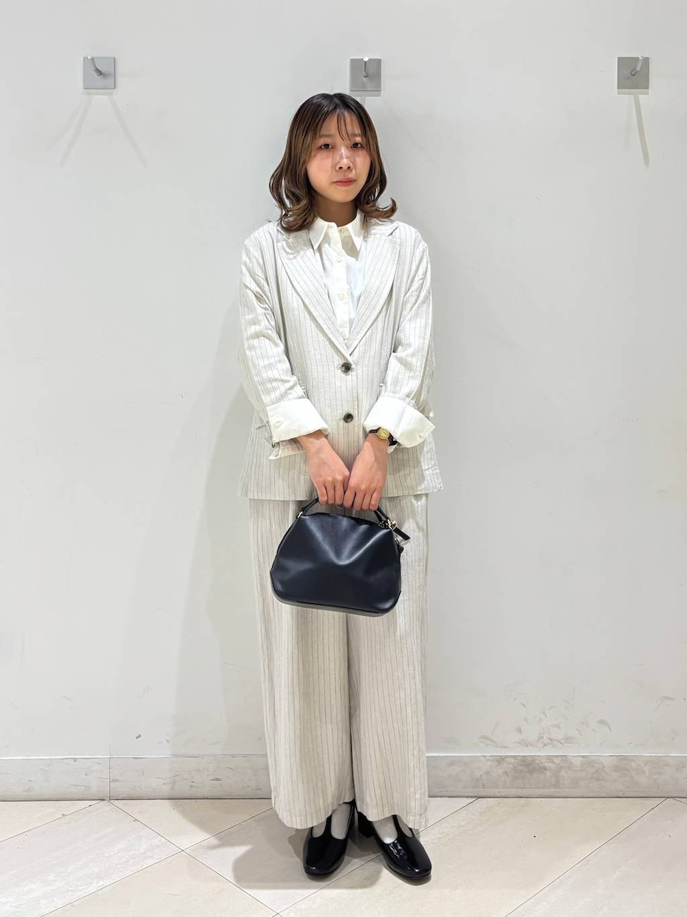 ブラック系のショルダーバッグ、ベージュ系のその他パンツ、グレー系のテーラードジャケットを着用したレディースの春コーディネートの2枚目の写真