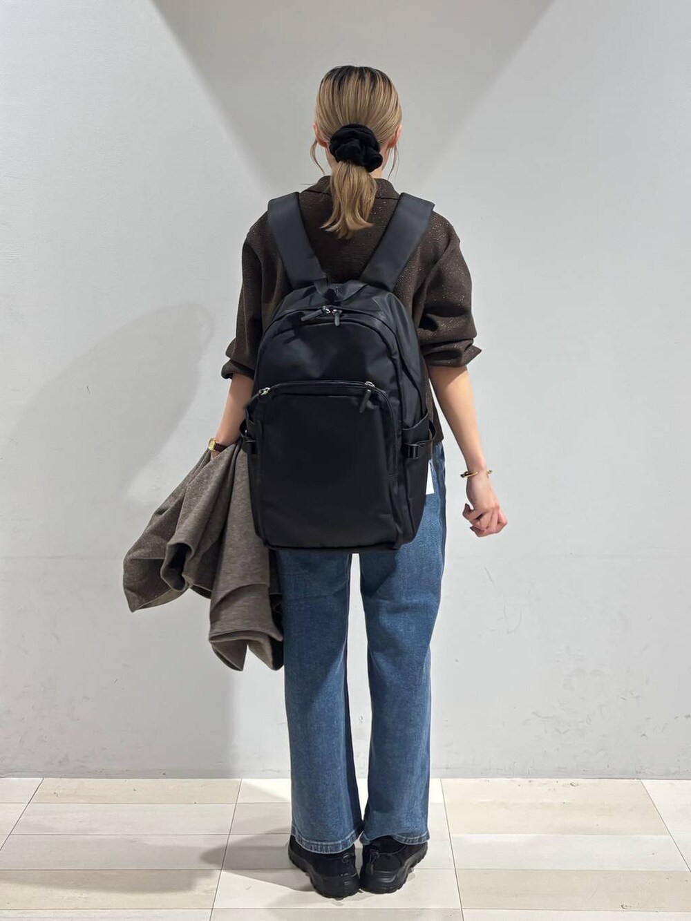 ブラック系のバックパック/リュック、ブラウン系のチェスターコート、ブラウン系のワンピースを着用したレディースの秋コーディネートの3枚目の写真