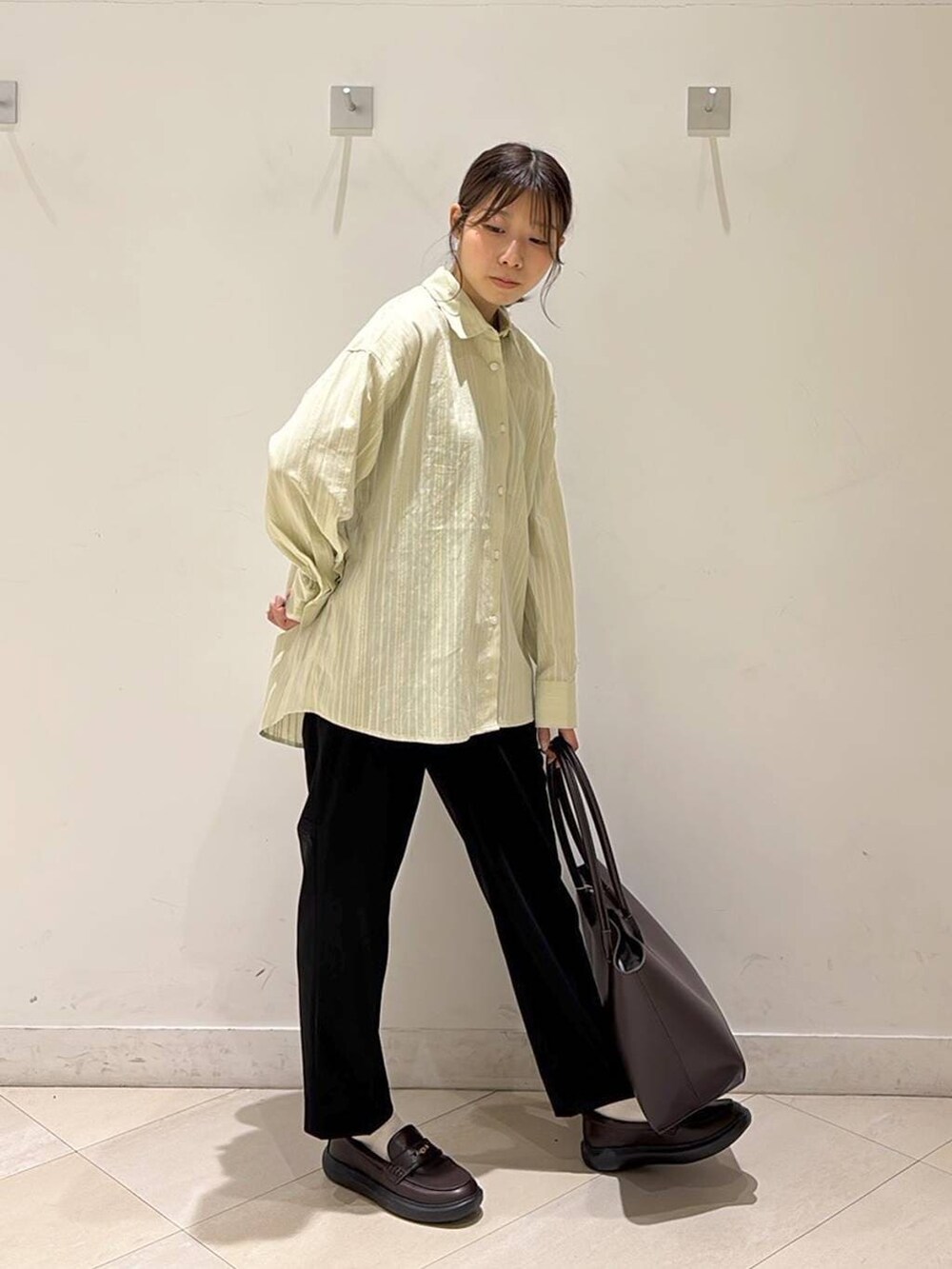 ブラック系のその他パンツ、ブラウン系のトートバッグ、ブラウン系のスニーカーを着用したレディースの春コーディネートの5枚目の写真