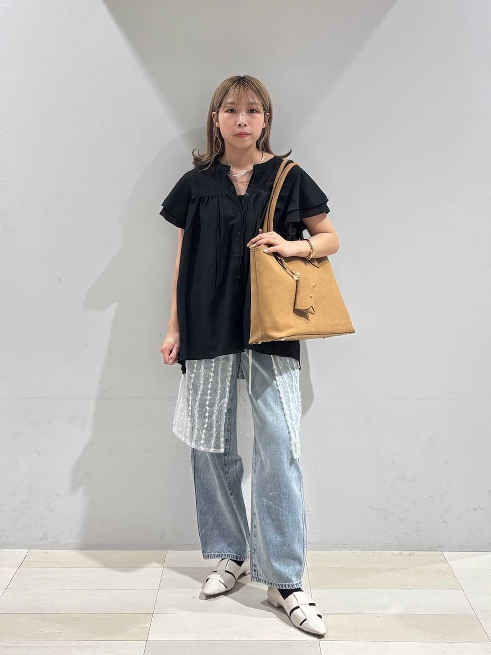 ブルー系のデニムパンツ、ホワイト系のパンプス、ベージュ系のトートバッグを着用したレディースの夏コーディネートの2枚目の写真