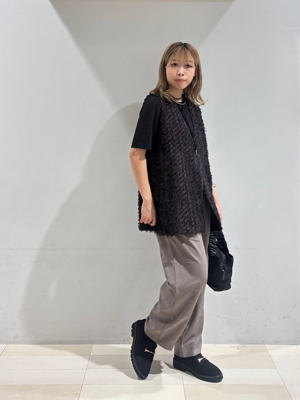 ブラック系のショルダーバッグ、ブラック系のTシャツ/カットソー、ブラック系のローファーを着用したレディースの秋コーディネートの8枚目の写真