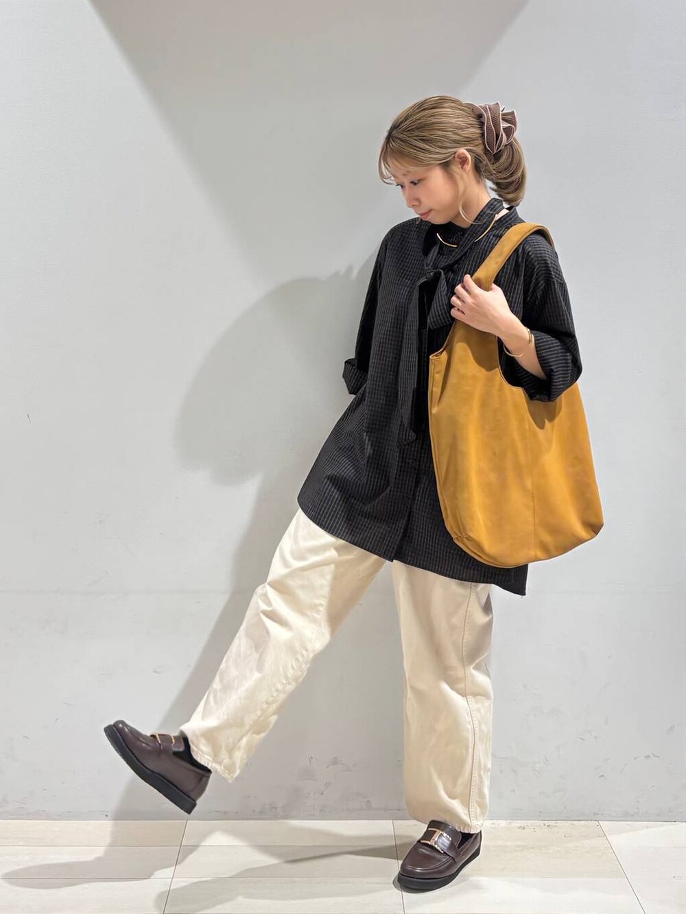 ベージュ系のデニムパンツ、ブラウン系のローファー、イエロー系のトートバッグを着用したレディースの夏コーディネートの2枚目の写真