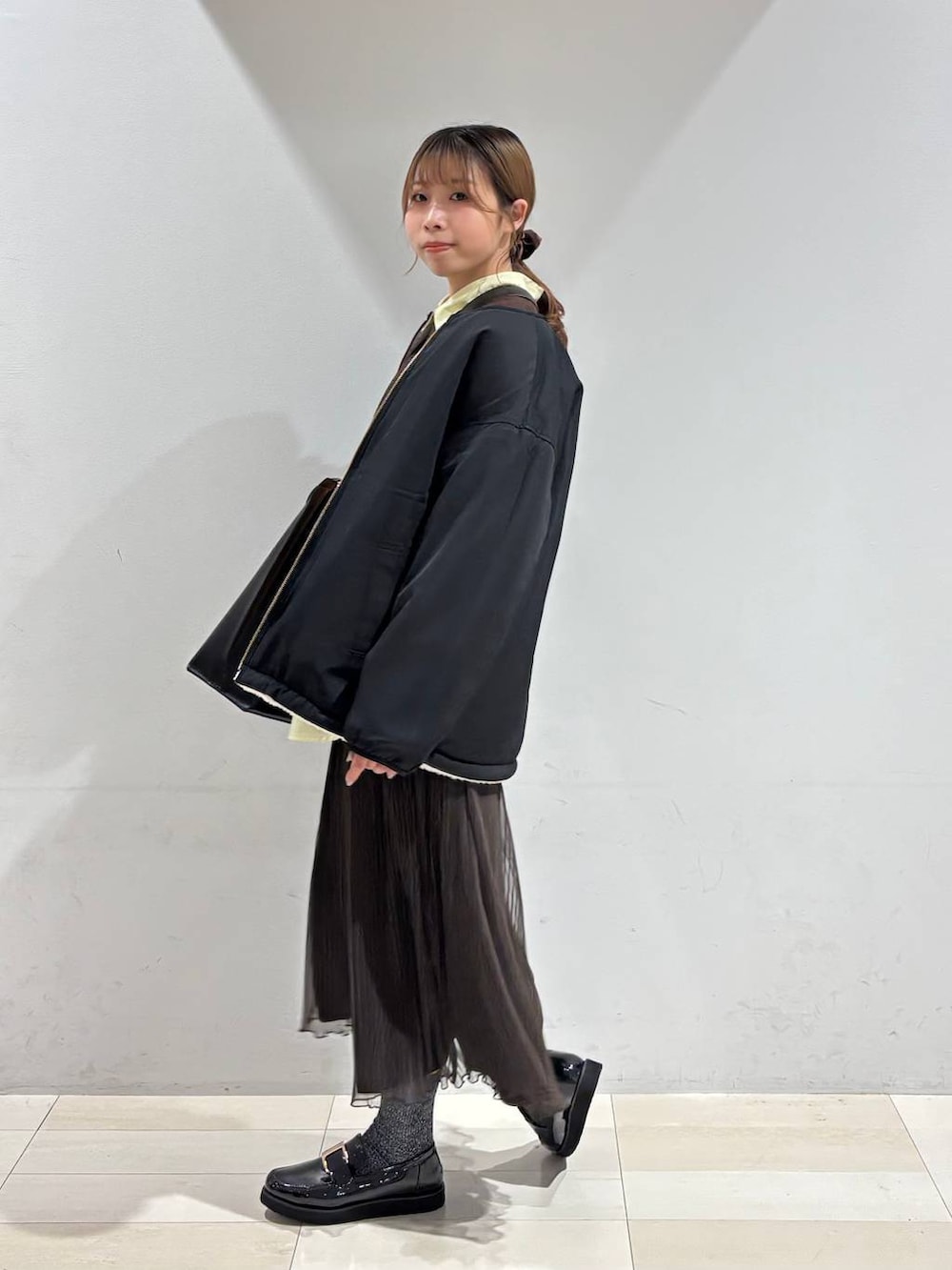 ブラック系のローファー、ブラック系のトートバッグ、ホワイト系のブルゾンを着用したレディースの秋コーディネートの6枚目の写真