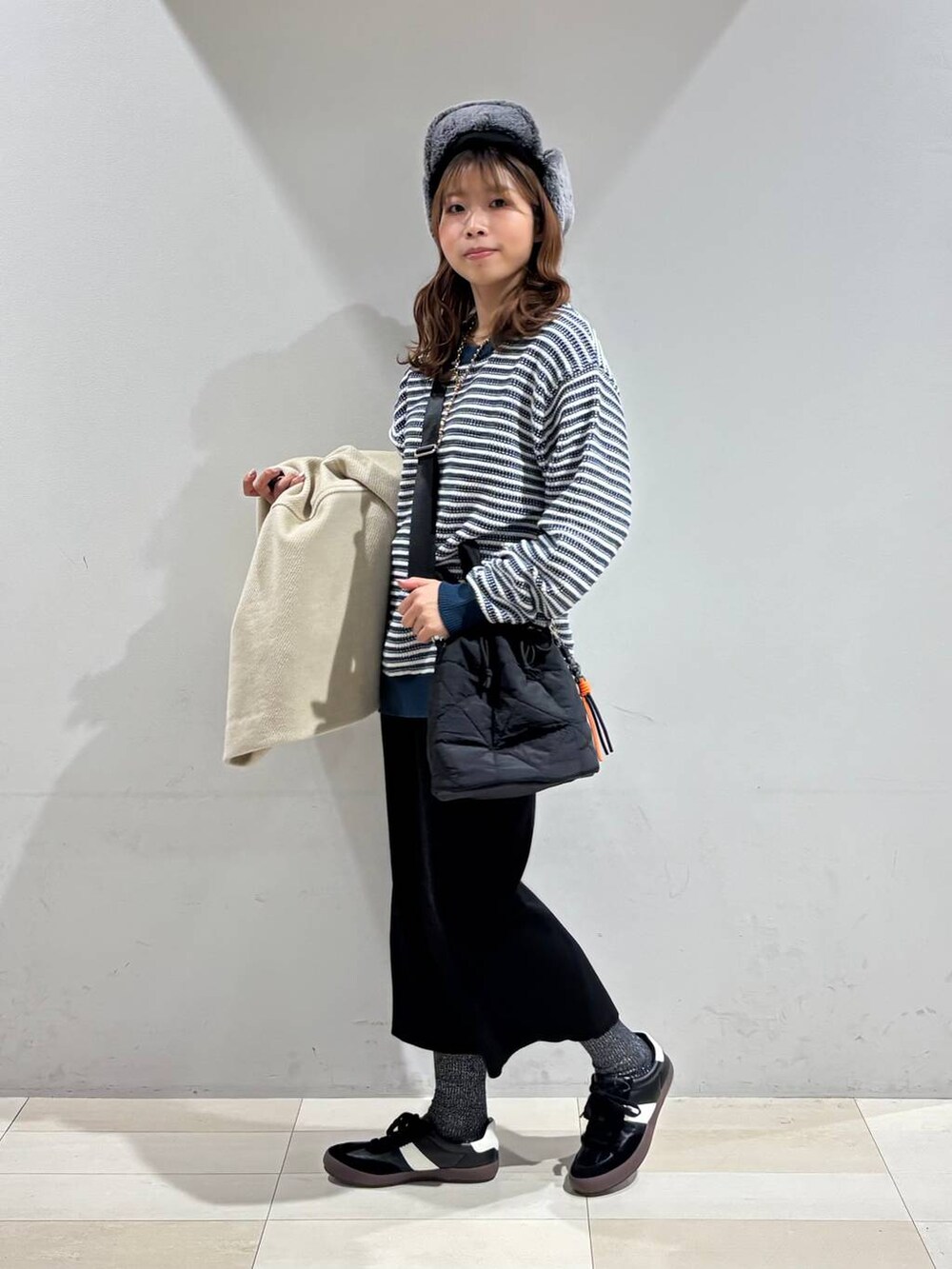 ブラック系のスニーカー、ブラック系のハンドバッグ、ブラック系のスカートを着用したレディースの冬コーディネートの2枚目の写真