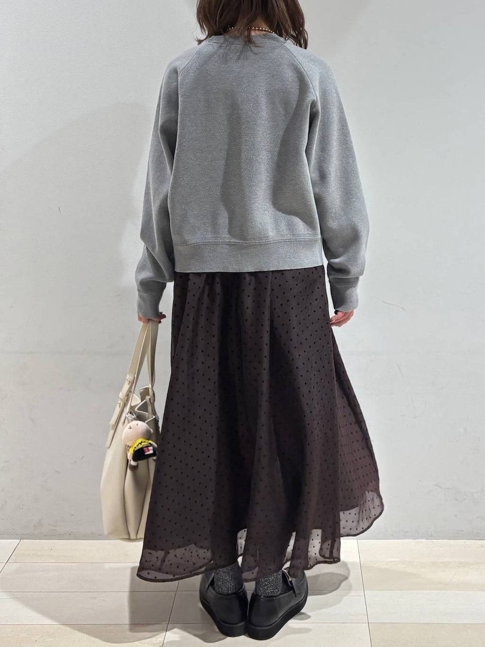 ブラック系のローファー、ホワイト系のハンドバッグ、ブラウン系のスカートを着用したレディースの春コーディネートの4枚目の写真