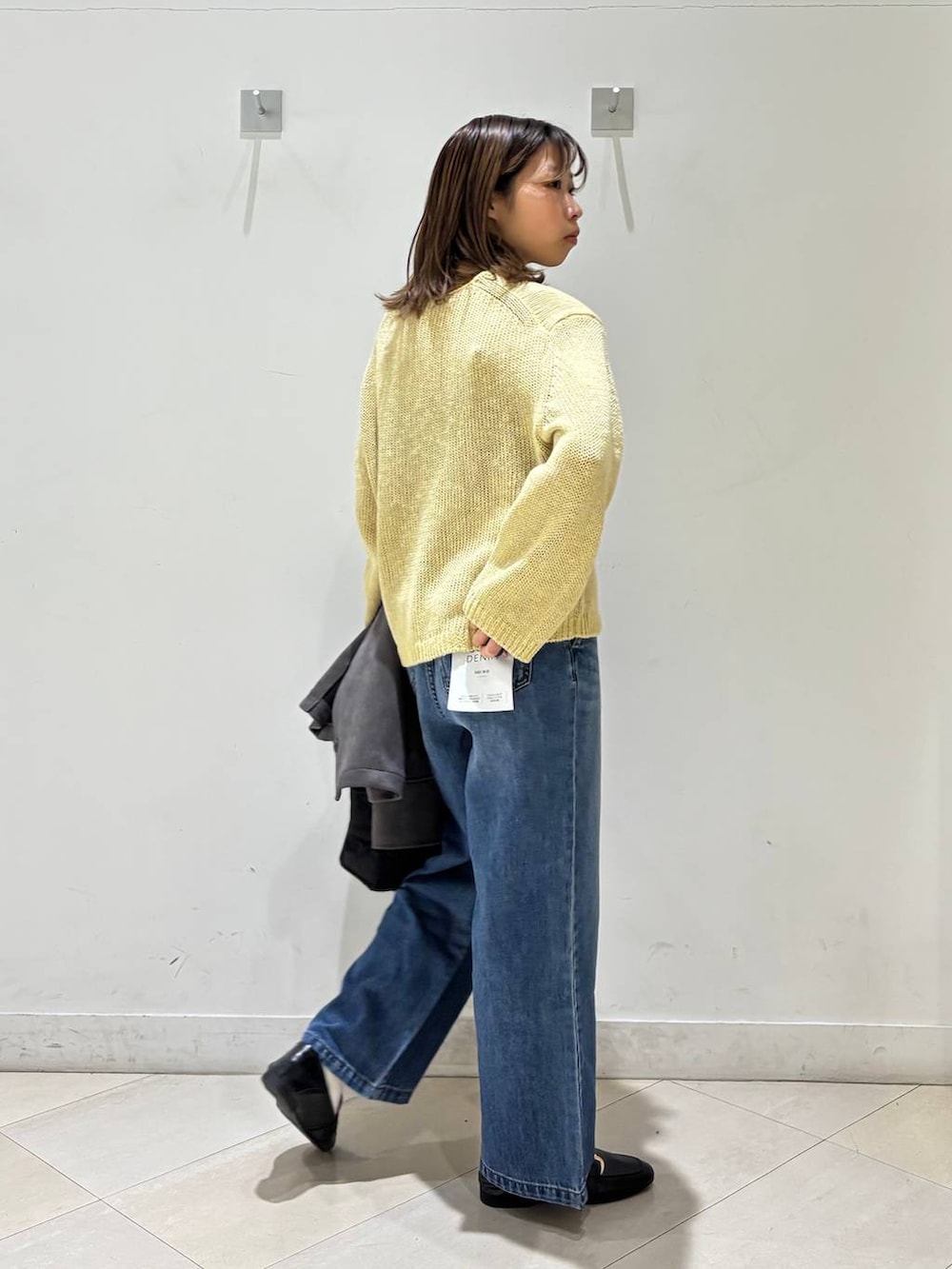 ブラック系のローファー、ブラック系のトートバッグ、ブルー系のデニムパンツを着用したレディースの春コーディネートの6枚目の写真