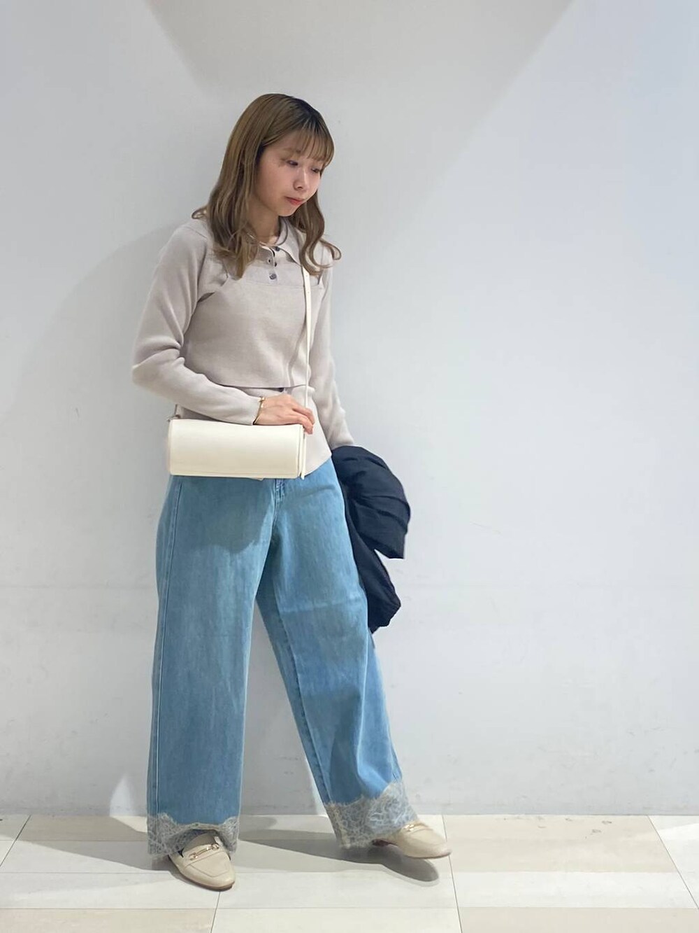 ベージュ系のTシャツ/カットソー、ホワイト系のクラッチバッグ、ホワイト系のローファーを着用したレディースの秋コーディネートの3枚目の写真