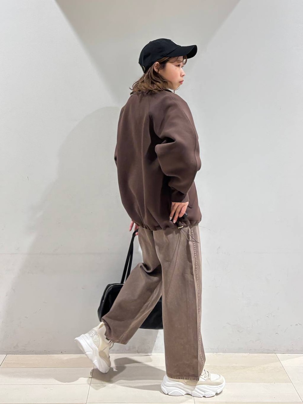 ブラウン系のデニムパンツ、ブラウン系のブルゾン、ゴールド系のスニーカーを着用したレディースの春コーディネートの6枚目の写真