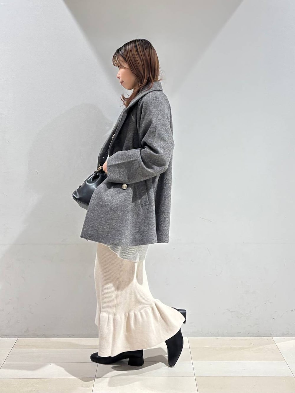 ブラック系のショルダーバッグ、グレー系のチェスターコート、グレー系のニット/セーターを着用したレディースの冬コーディネートの4枚目の写真