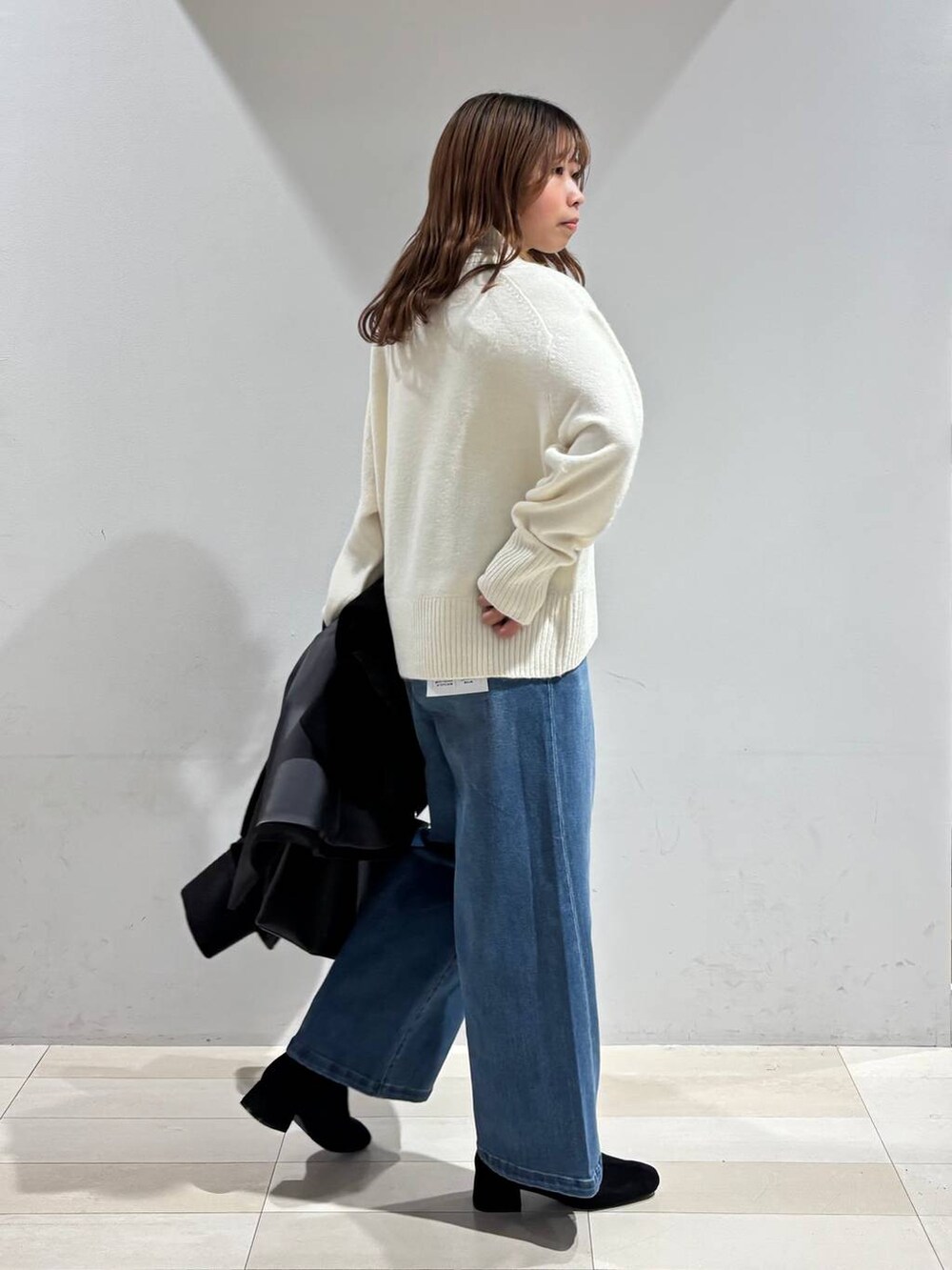 ブラック系のショルダーバッグ、ブラック系のチェスターコート、ホワイト系のニット/セーターを着用したレディースの冬コーディネートの5枚目の写真