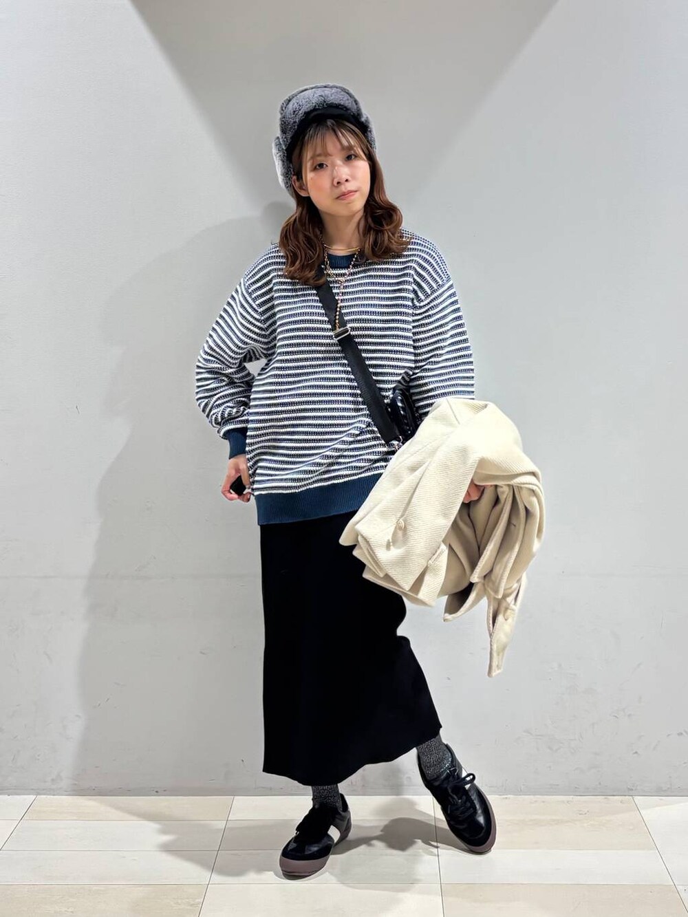 ブラック系のスニーカー、ブラック系のハンドバッグ、ブラック系のスカートを着用したレディースの冬コーディネートの4枚目の写真