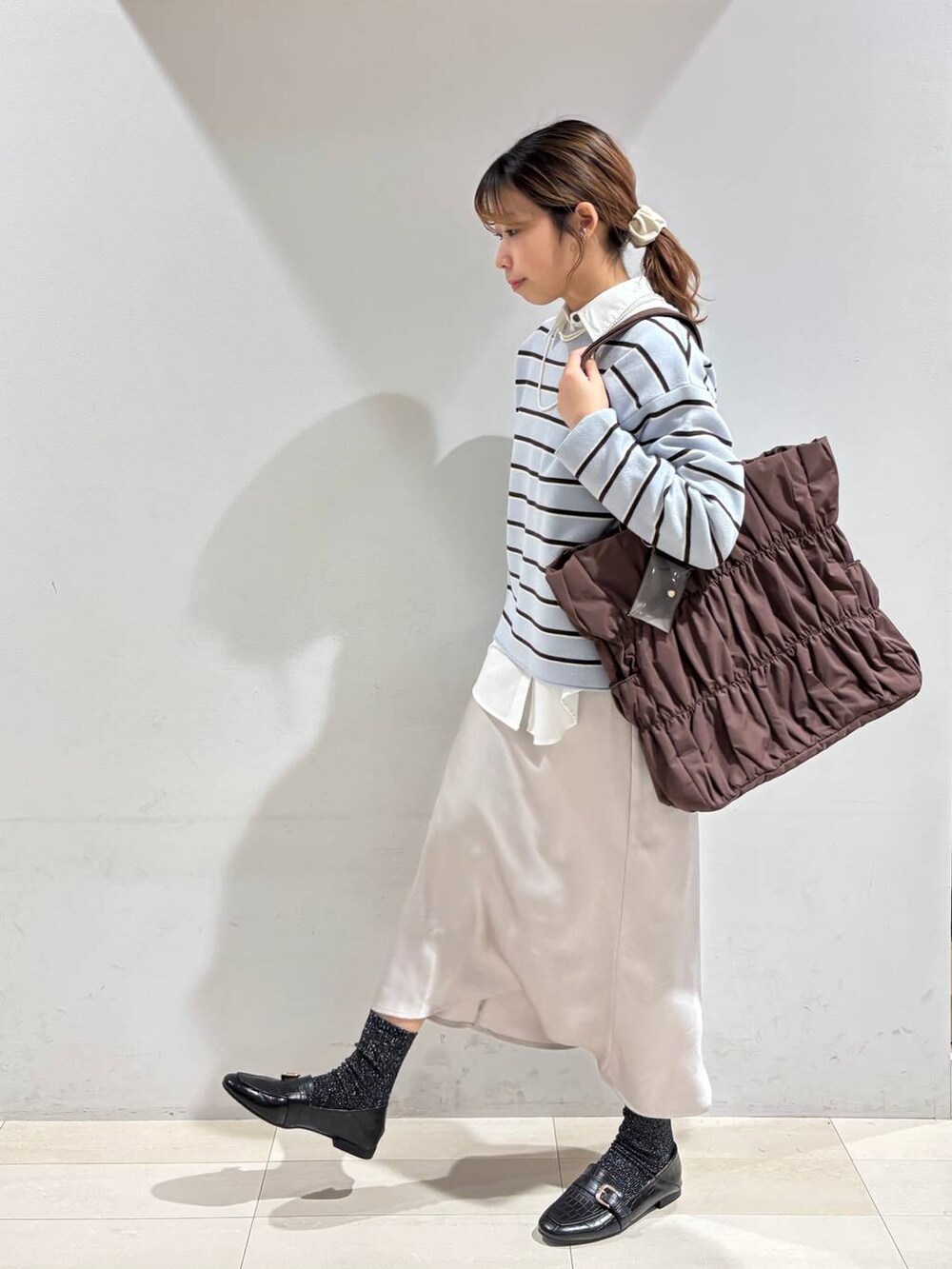 ブラック系のローファー、ブラウン系のトートバッグ、ブルー系のニット/セーターを着用したレディースの冬コーディネートの3枚目の写真