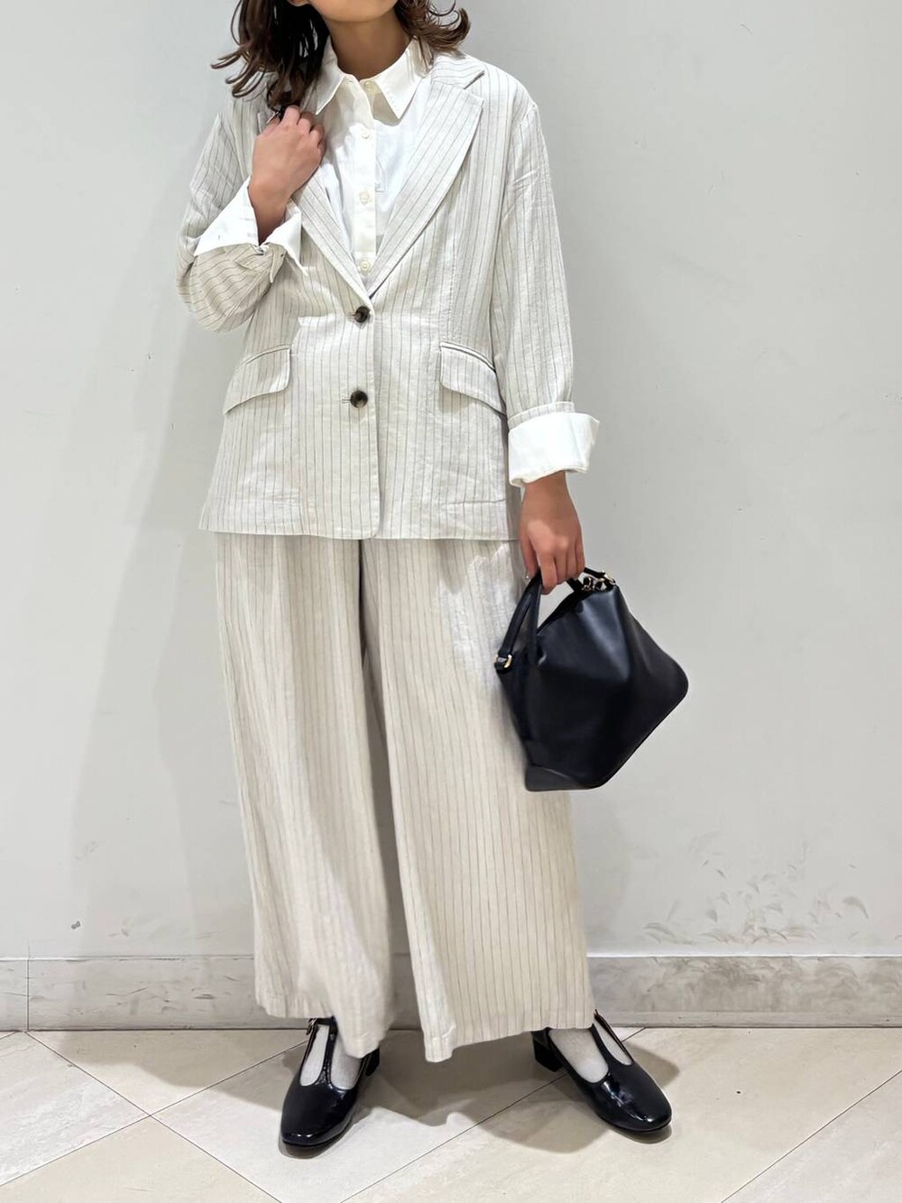 ブラック系のショルダーバッグ、ベージュ系のその他パンツ、グレー系のテーラードジャケットを着用したレディースの春コーディネートの10枚目の写真