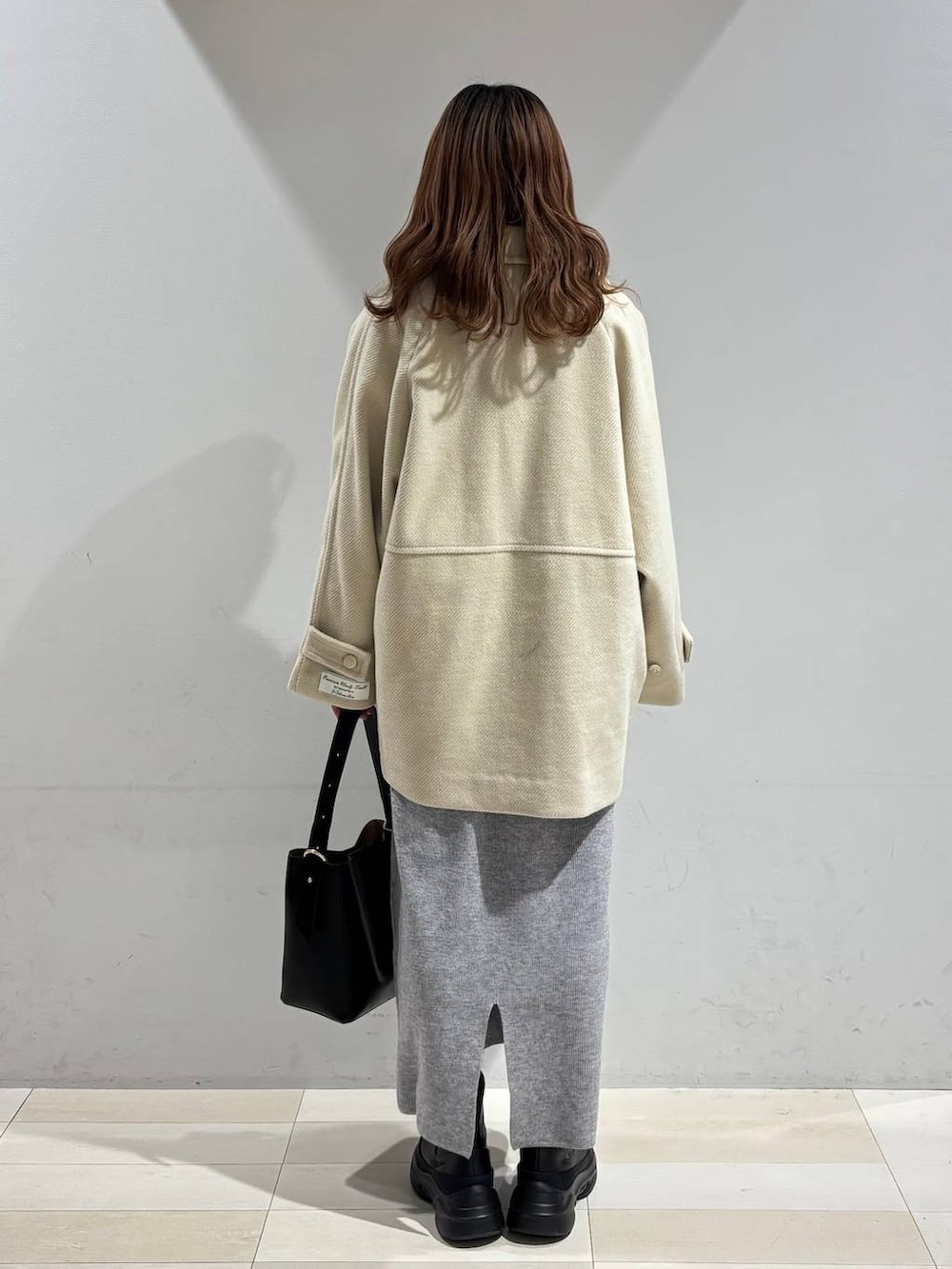 ブラック系のショルダーバッグ、グレー系のワンピース、ブラック系のブーツを着用したレディースの冬コーディネートの4枚目の写真