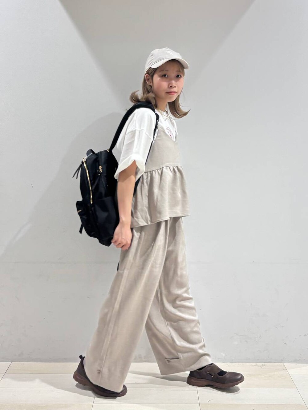 ブラウン系のスニーカー、ブラック系のバックパック/リュック、ベージュ系のサロペット/オーバーオールを着用したレディースの夏コーディネートの2枚目の写真