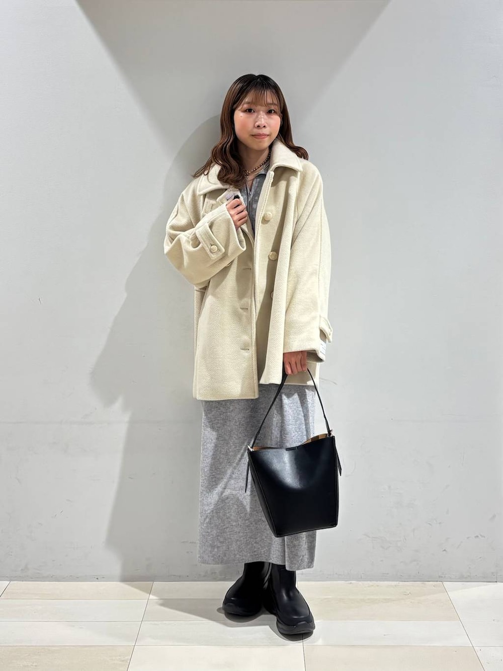 ブラック系のショルダーバッグ、グレー系のワンピース、ブラック系のブーツを着用したレディースの冬コーディネートの2枚目の写真