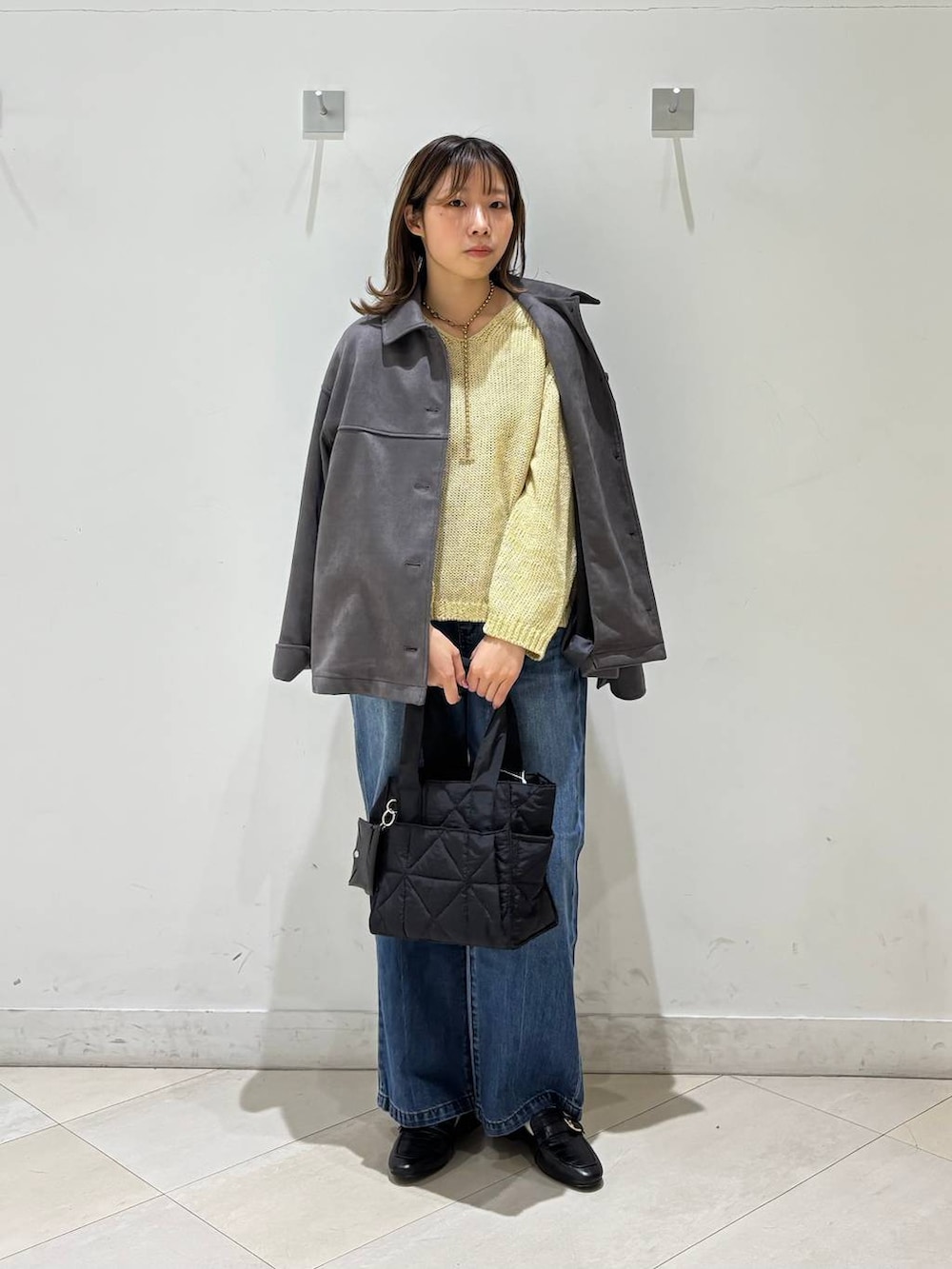 ブラック系のローファー、ブラック系のトートバッグ、ブルー系のデニムパンツを着用したレディースの春コーディネートの7枚目の写真