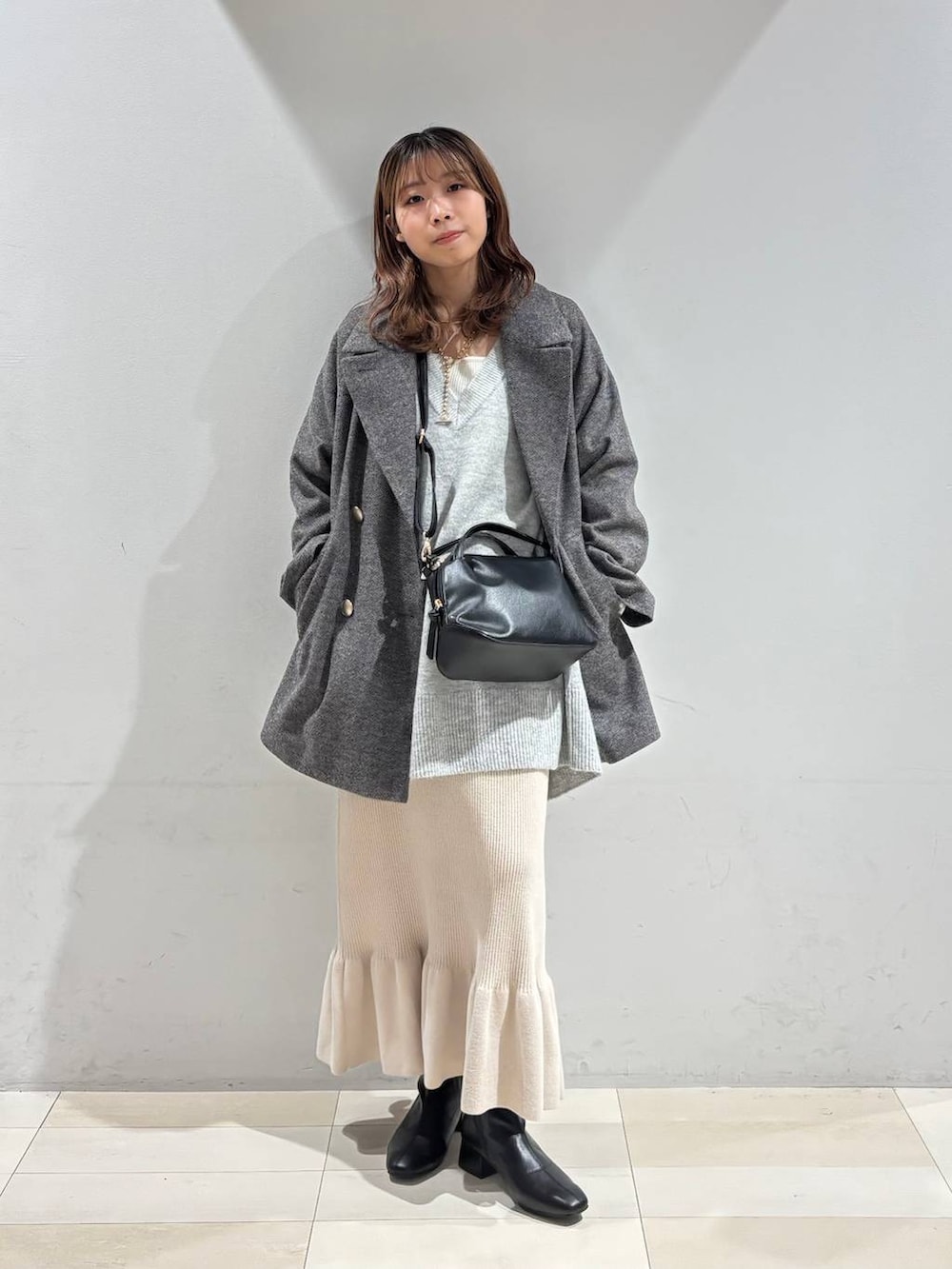ブラック系のショルダーバッグ、グレー系のチェスターコート、グレー系のニット/セーターを着用したレディースの冬コーディネートの6枚目の写真