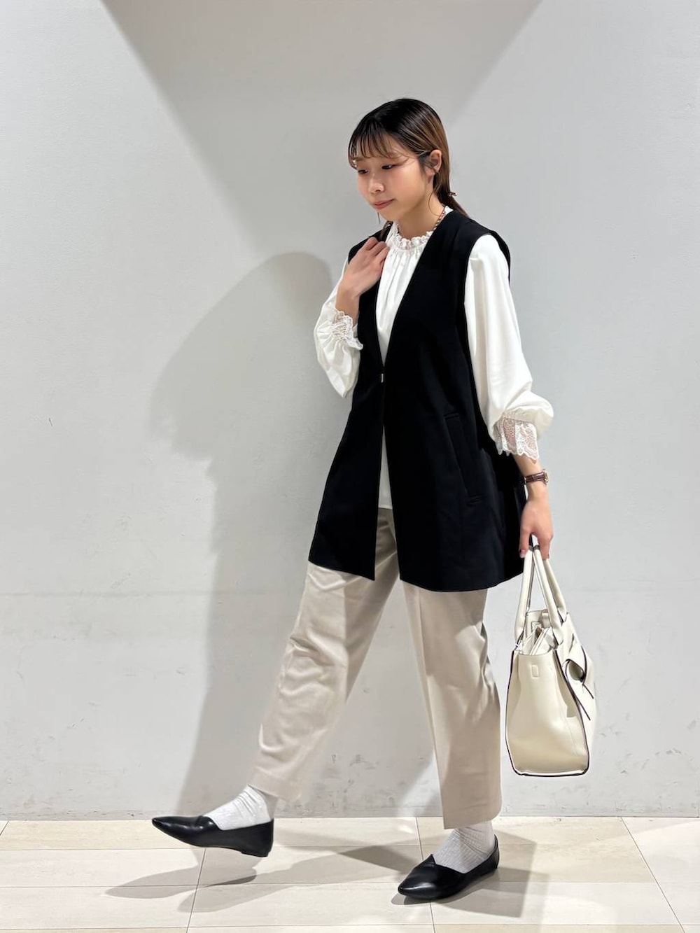 ブラック系のパンプス、ベージュ系のスラックス、ホワイト系のシャツ/ブラウスを着用したレディースの冬コーディネートの2枚目の写真