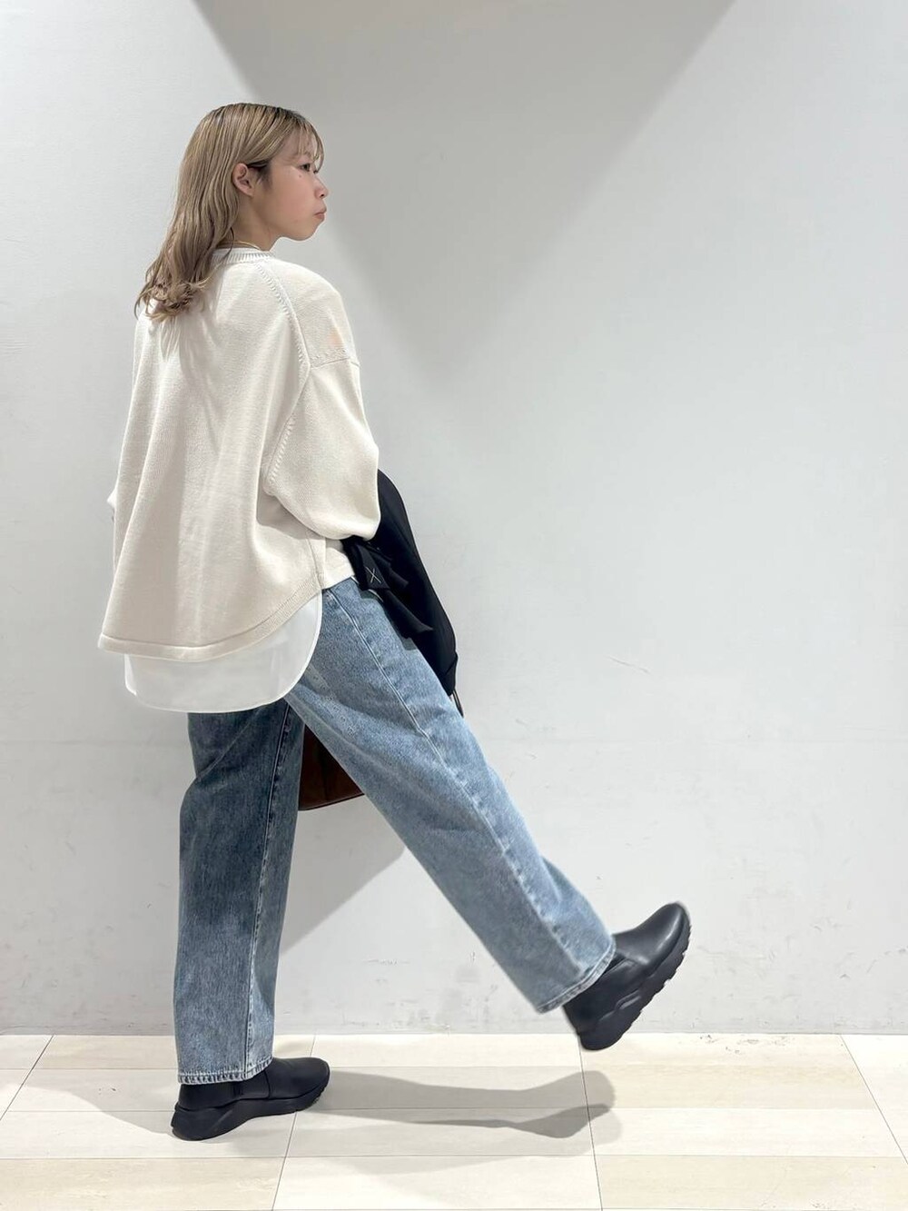 ベージュ系のニット/セーター、ブラウン系のボストンバッグ、ブルー系のデニムパンツを着用したレディースの秋コーディネートの6枚目の写真
