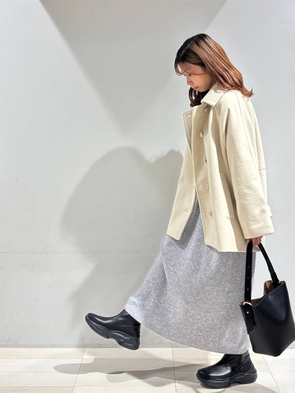 ブラック系のショルダーバッグ、グレー系のワンピース、ブラック系のブーツを着用したレディースの冬コーディネートの3枚目の写真