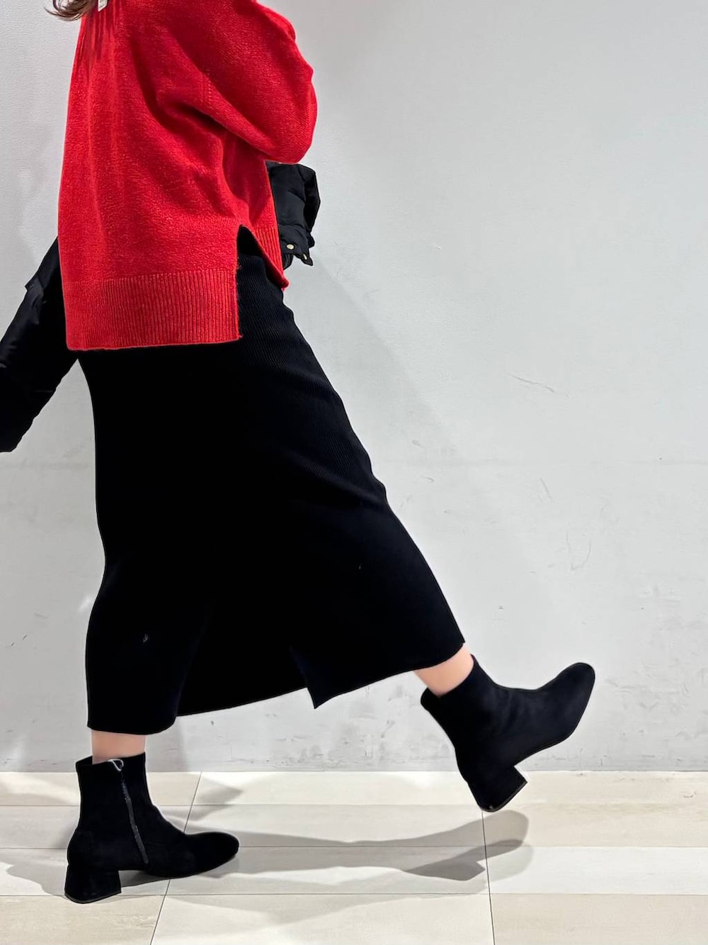 ブラウン系のボストンバッグ、ブラック系のダウンジャケット/コート、ブラック系のスカートを着用したレディースの冬コーディネートの2枚目の写真