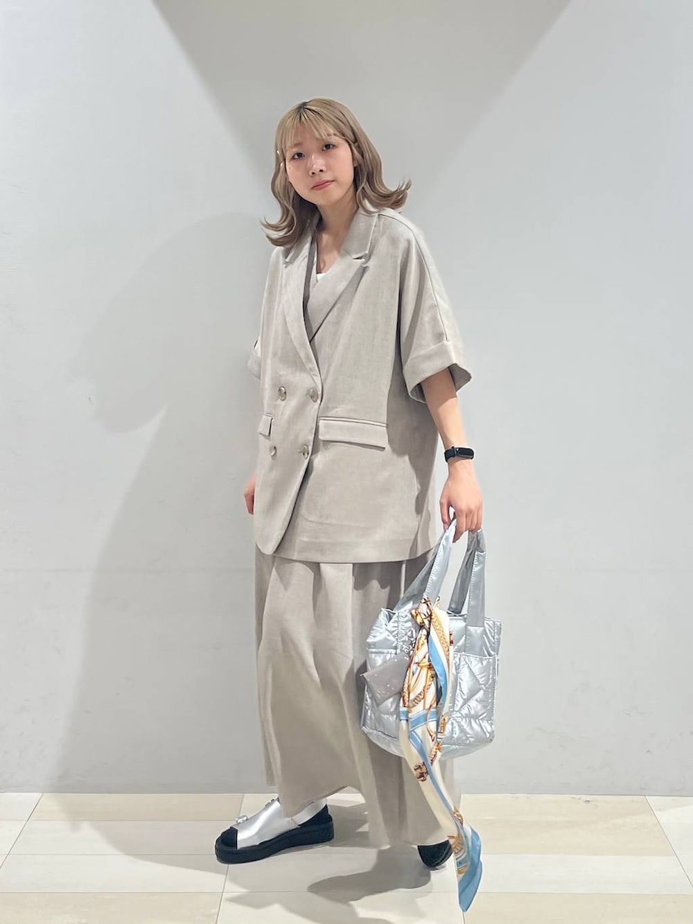 シルバー系のトートバッグ、ホワイト系のキャミソール、シルバー系のサンダルを着用したレディースの夏コーディネートの3枚目の写真