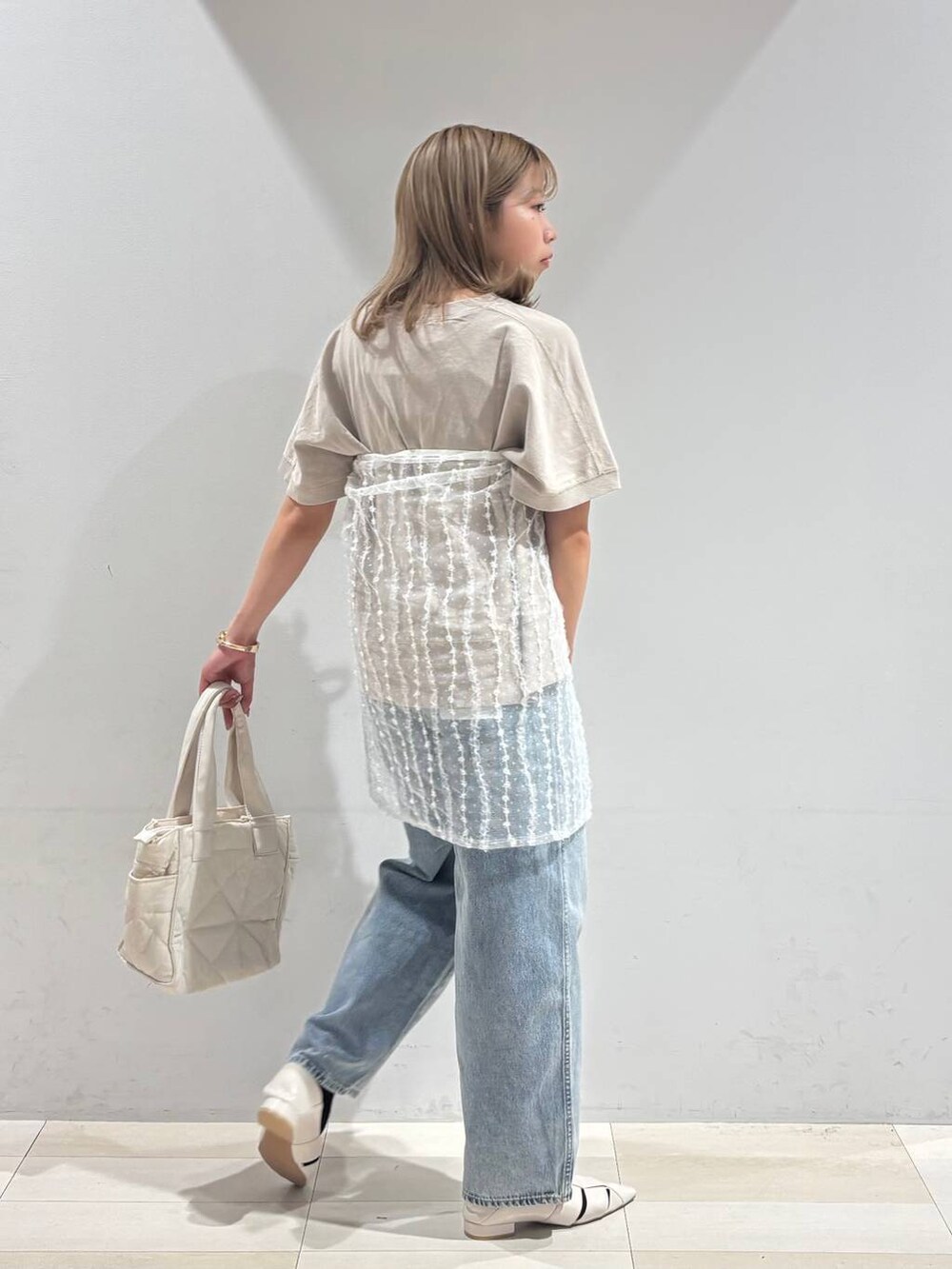 ブルー系のデニムパンツ、ホワイト系のトートバッグ、ホワイト系のパンプスを着用したレディースの夏コーディネートの5枚目の写真