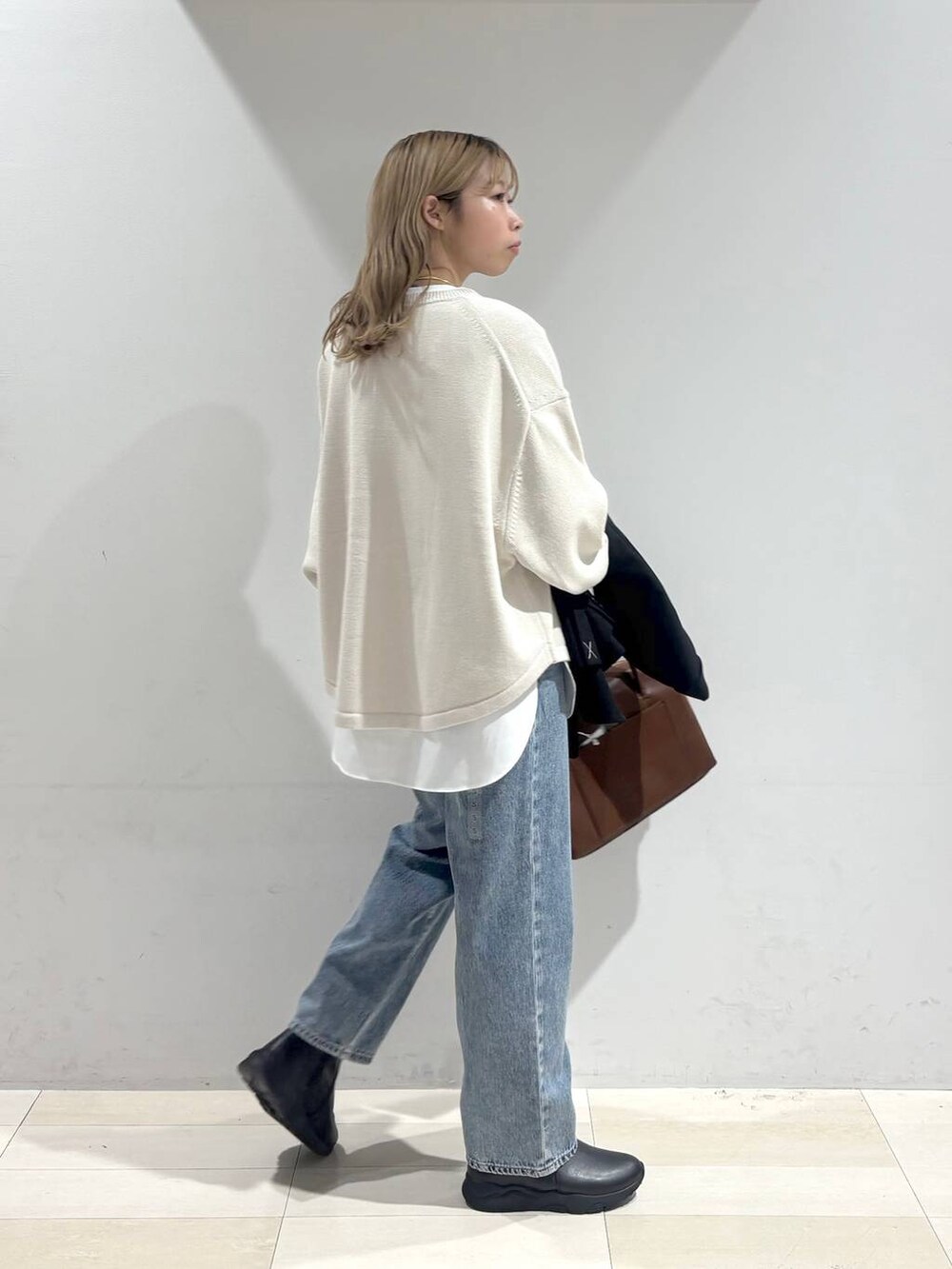 ベージュ系のニット/セーター、ブラウン系のボストンバッグ、ブルー系のデニムパンツを着用したレディースの秋コーディネートの7枚目の写真