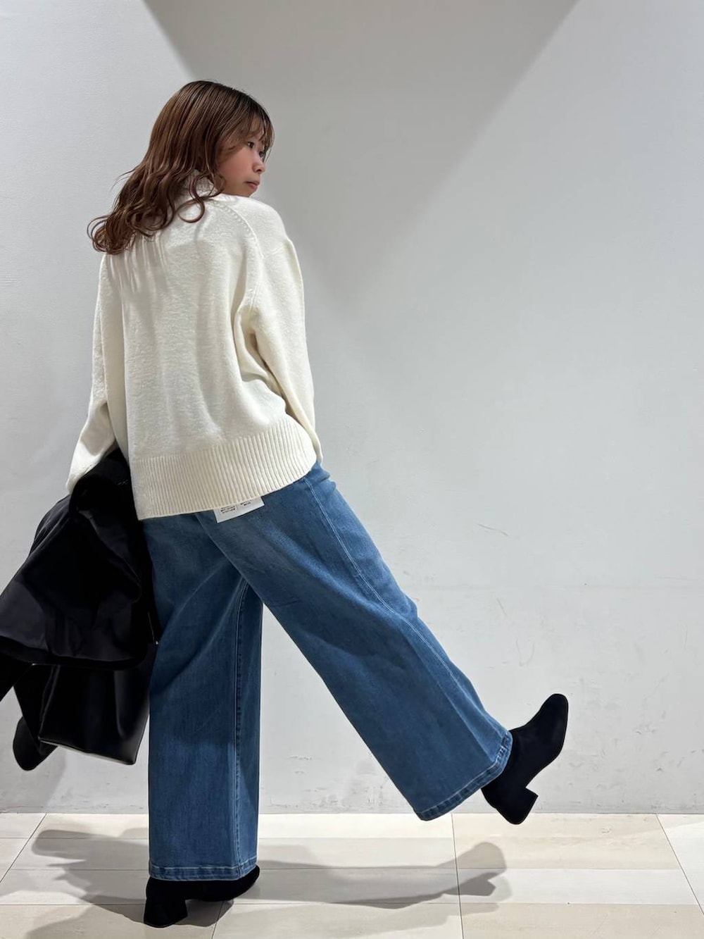 ブラック系のショルダーバッグ、ブラック系のチェスターコート、ホワイト系のニット/セーターを着用したレディースの冬コーディネートの4枚目の写真