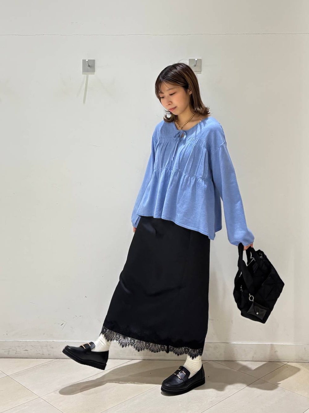 ブラック系のローファー、ブラック系のトートバッグ、ブルー系のカーディガン/ボレロを着用したレディースの春コーディネートの3枚目の写真