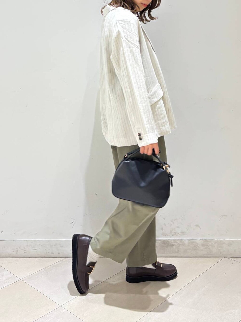 ブラック系のショルダーバッグ、ブラウン系のローファー、ブラック系のキャミソールを着用したレディースの春コーディネートの5枚目の写真