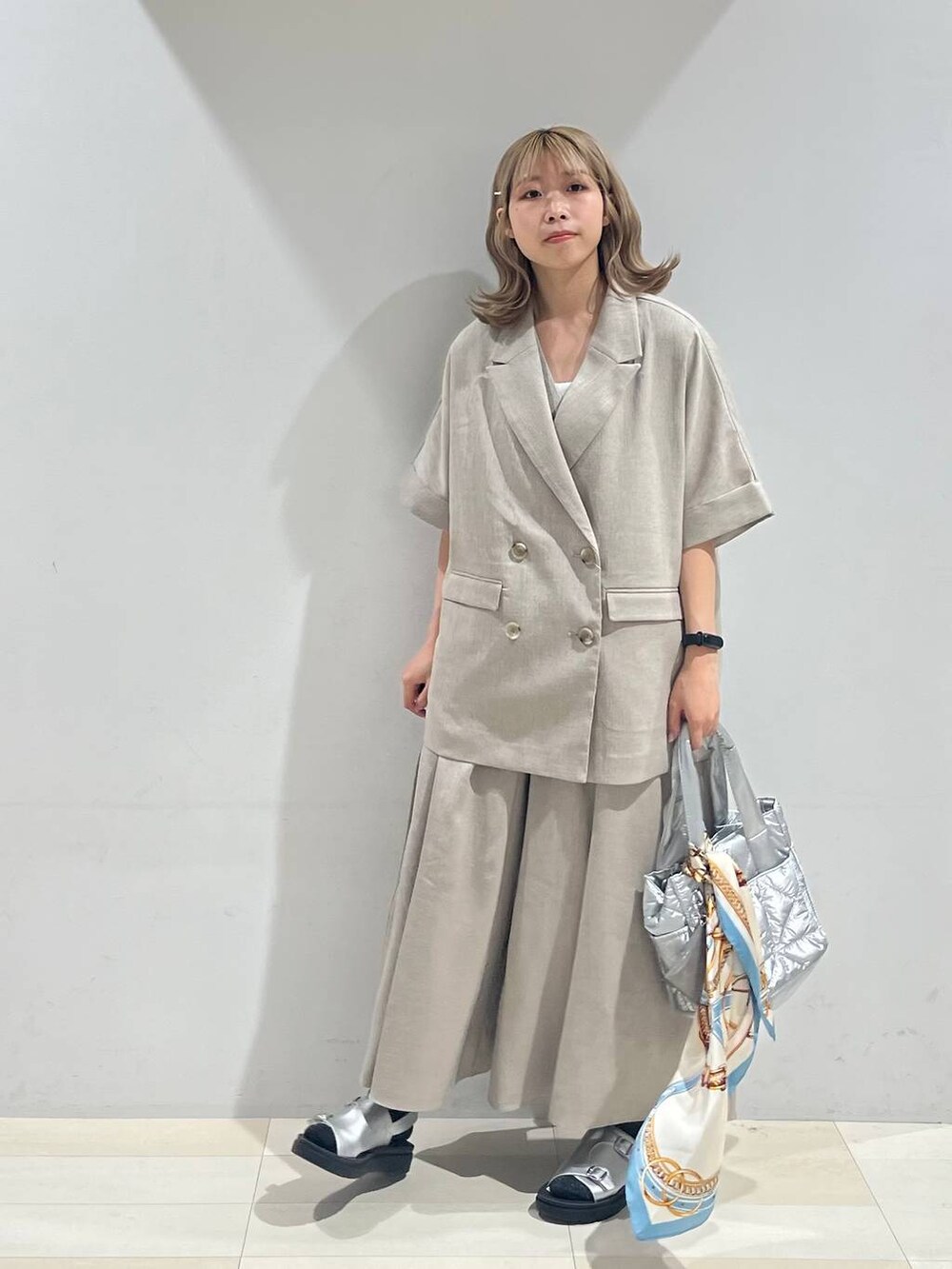 シルバー系のトートバッグ、ホワイト系のキャミソール、シルバー系のサンダルを着用したレディースの夏コーディネートの2枚目の写真