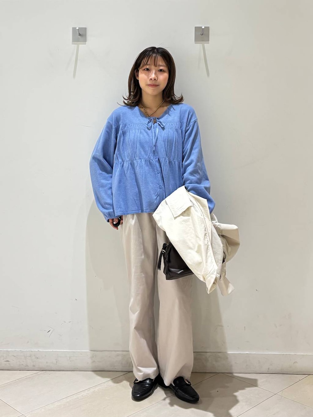 ブラック系のローファー、ホワイト系のその他パンツ、ブラウン系のボストンバッグを着用したレディースの春コーディネートの2枚目の写真