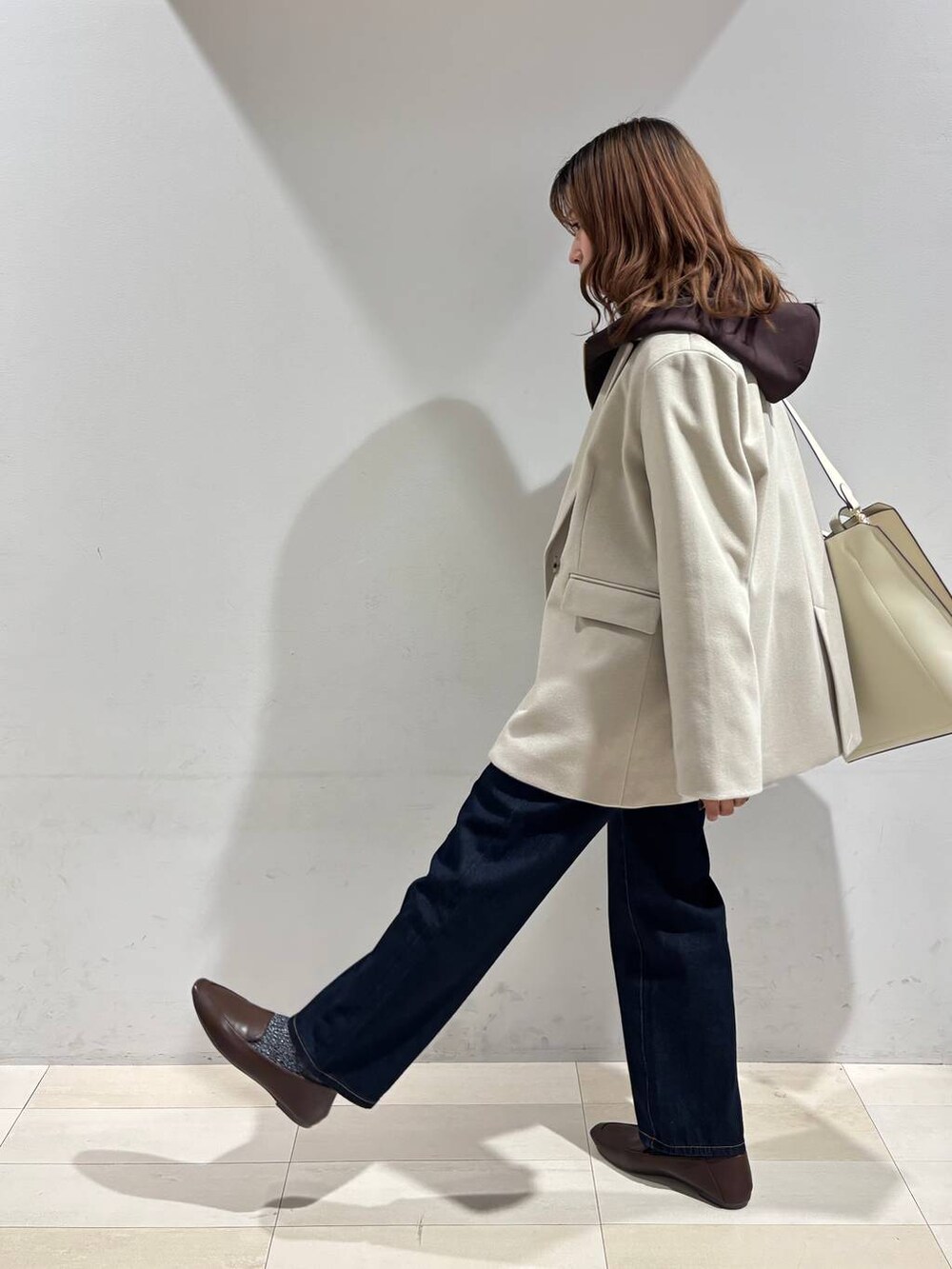 ホワイト系のトートバッグ、ブルー系のデニムパンツ、ベージュ系のテーラードジャケットを着用したレディースの冬コーディネートの7枚目の写真