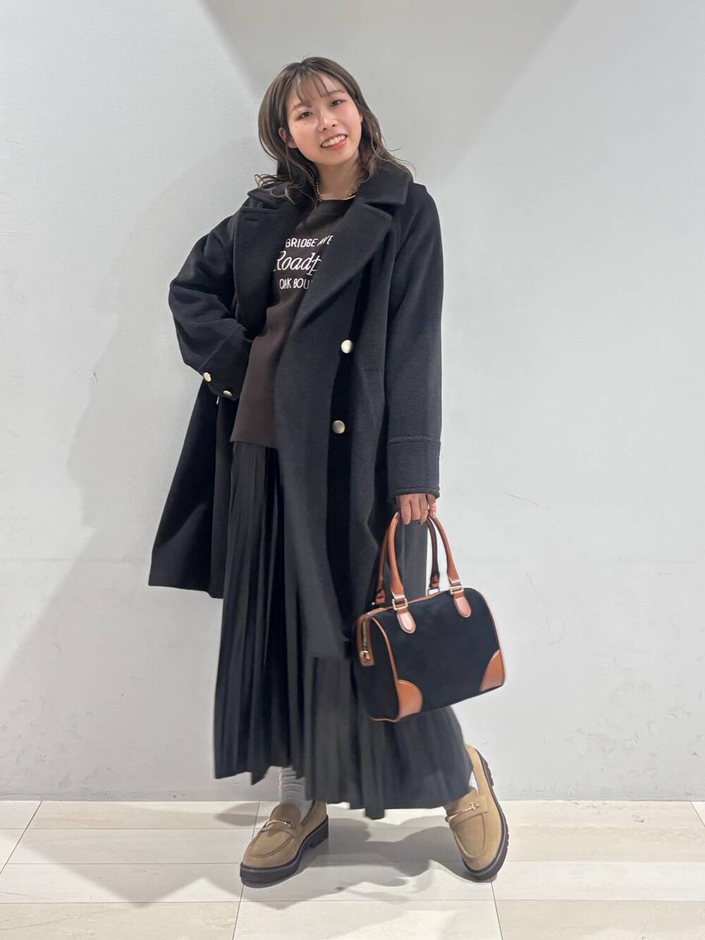 ブラック系のチェスターコート、ベージュ系のローファー、ブラック系のスカートを着用したレディースの秋コーディネートの3枚目の写真