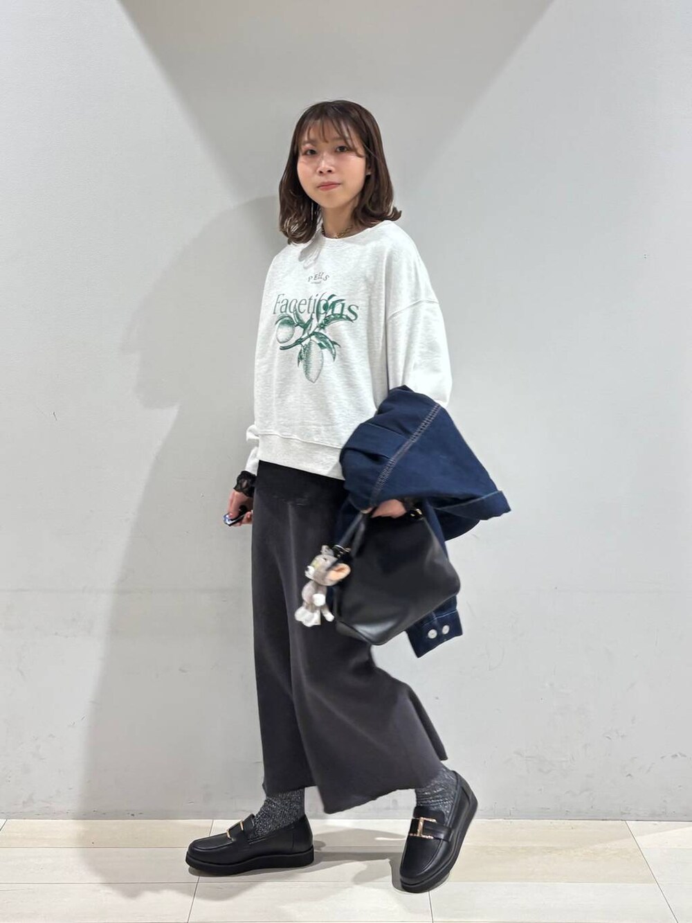 ブラック系のショルダーバッグ、ブラック系のローファー、ブラック系のTシャツ/カットソーを着用したレディースの冬コーディネートの3枚目の写真