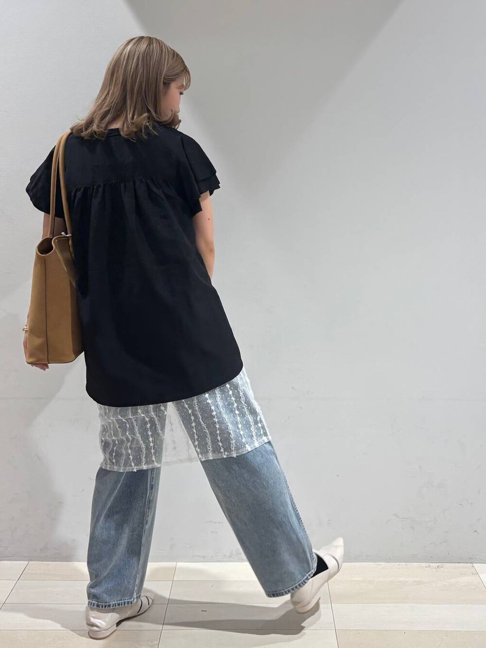 ブルー系のデニムパンツ、ホワイト系のパンプス、ベージュ系のトートバッグを着用したレディースの夏コーディネートの5枚目の写真