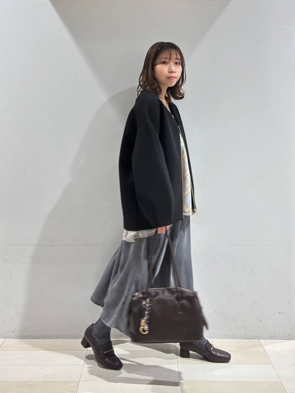 ブラウン系のローファー、ブラウン系のボストンバッグ、ブラック系のブルゾンを着用したレディースの春コーディネートの3枚目の写真